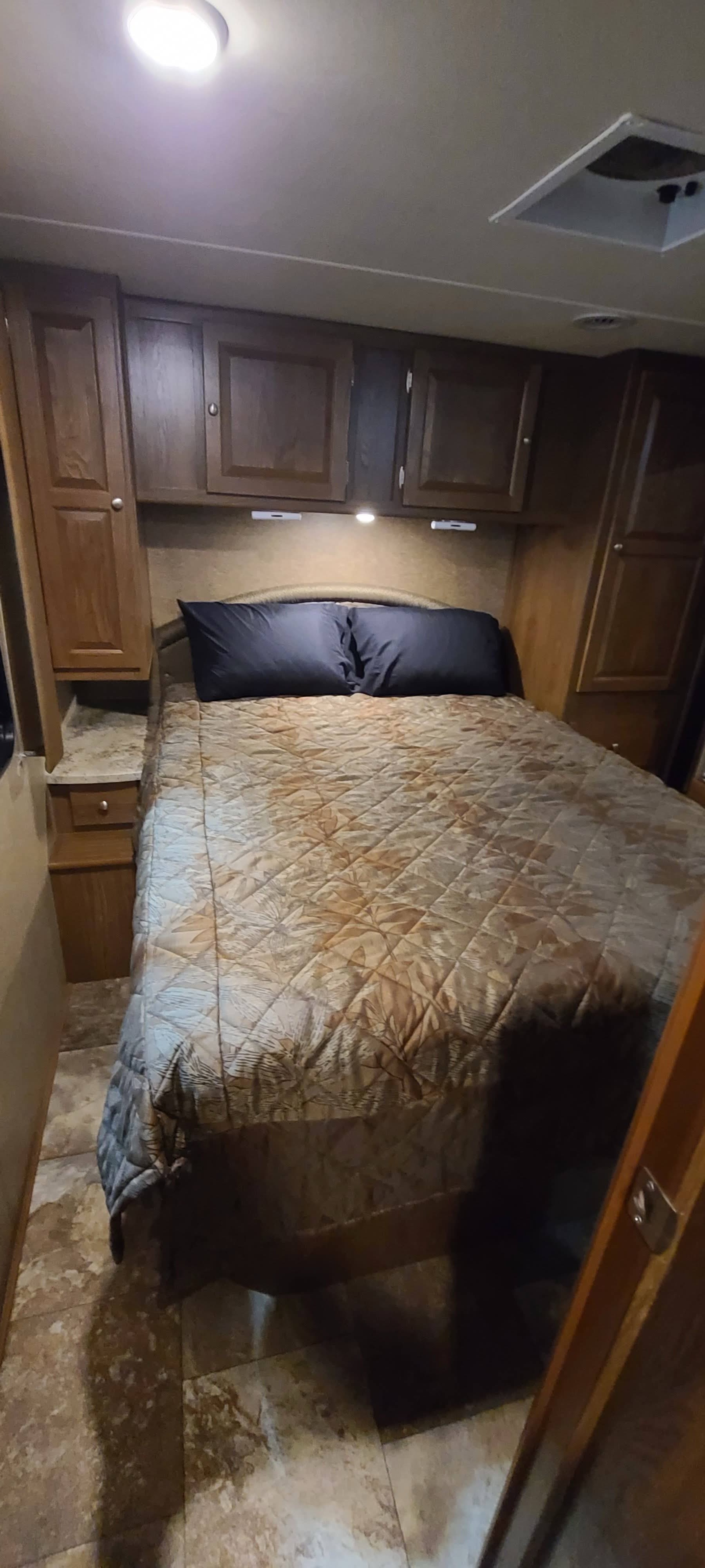 Inside an RV rental: a compact bedroom featuring a bed, ample storage, and ceiling lights.. Forest River Coachmen Leprechaun 2015