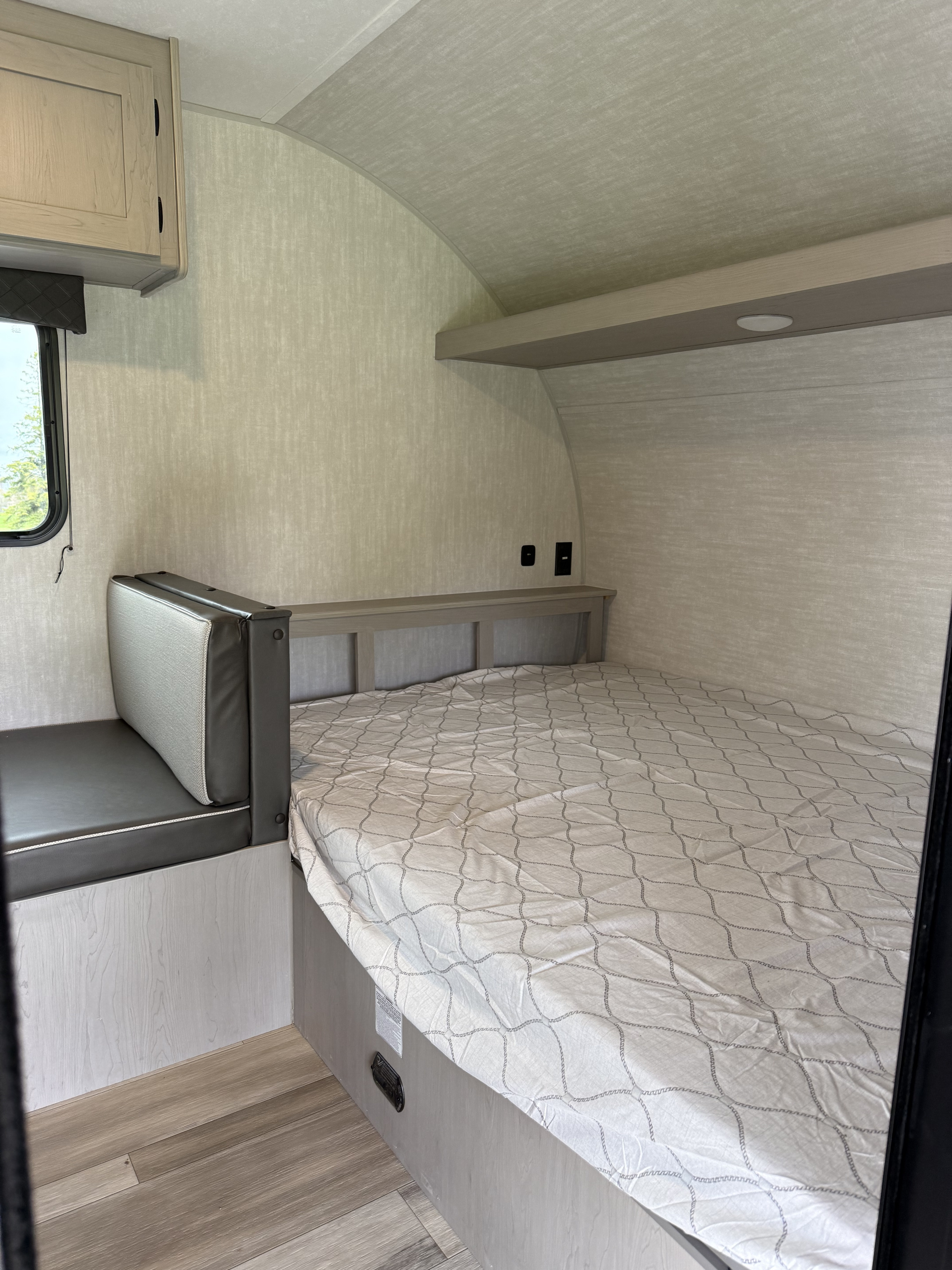 RV rental sleeping area with a bed, upholstered bench, and overhead cabinet.. Coachmen Clipper 17CBH 2025