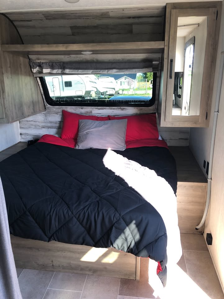 RV rental interior: A modern bedroom with a comfy bed, large window, and light wood accents.. Forest River Palomino Puma 2023