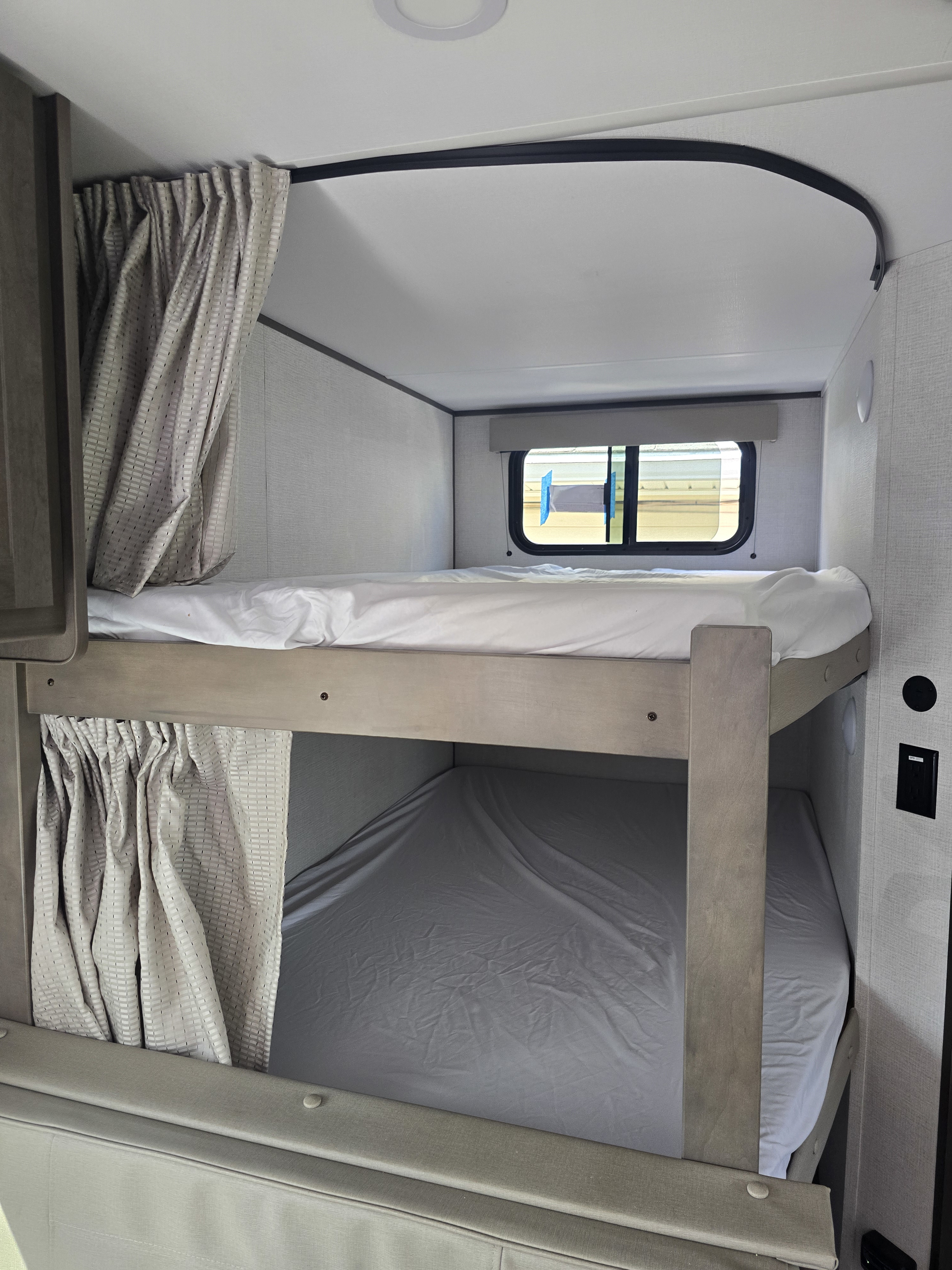 Cozy RV rental bunk beds with privacy curtains and a window, perfect for family travel comfort.. Grand design Transcend Xplor 2025
