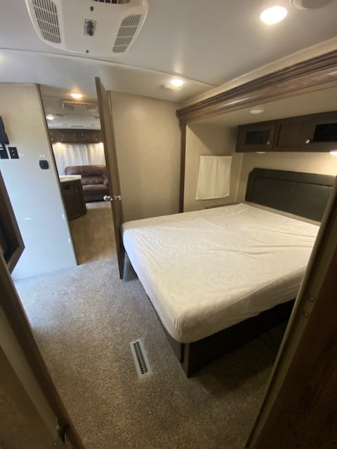 Inside an RV rental: a well-appointed bedroom with a bed and cabinets.. Forest River Rockwood Windjammer 2019