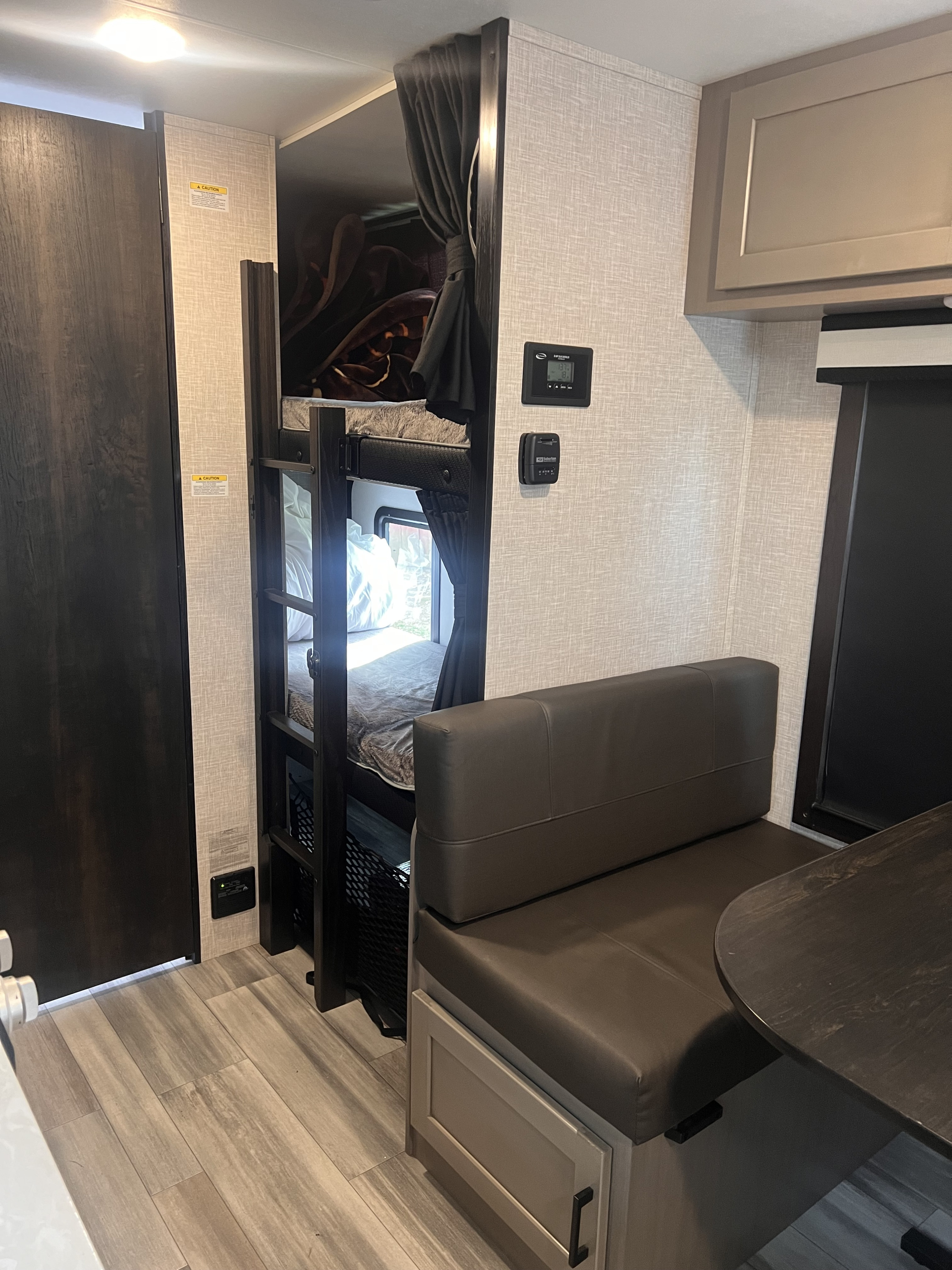 Cozy RV rental interior with bunk beds, privacy curtains, and a compact dinette. Showcases efficient living space.. Jayco Jay Feather Micro 2024