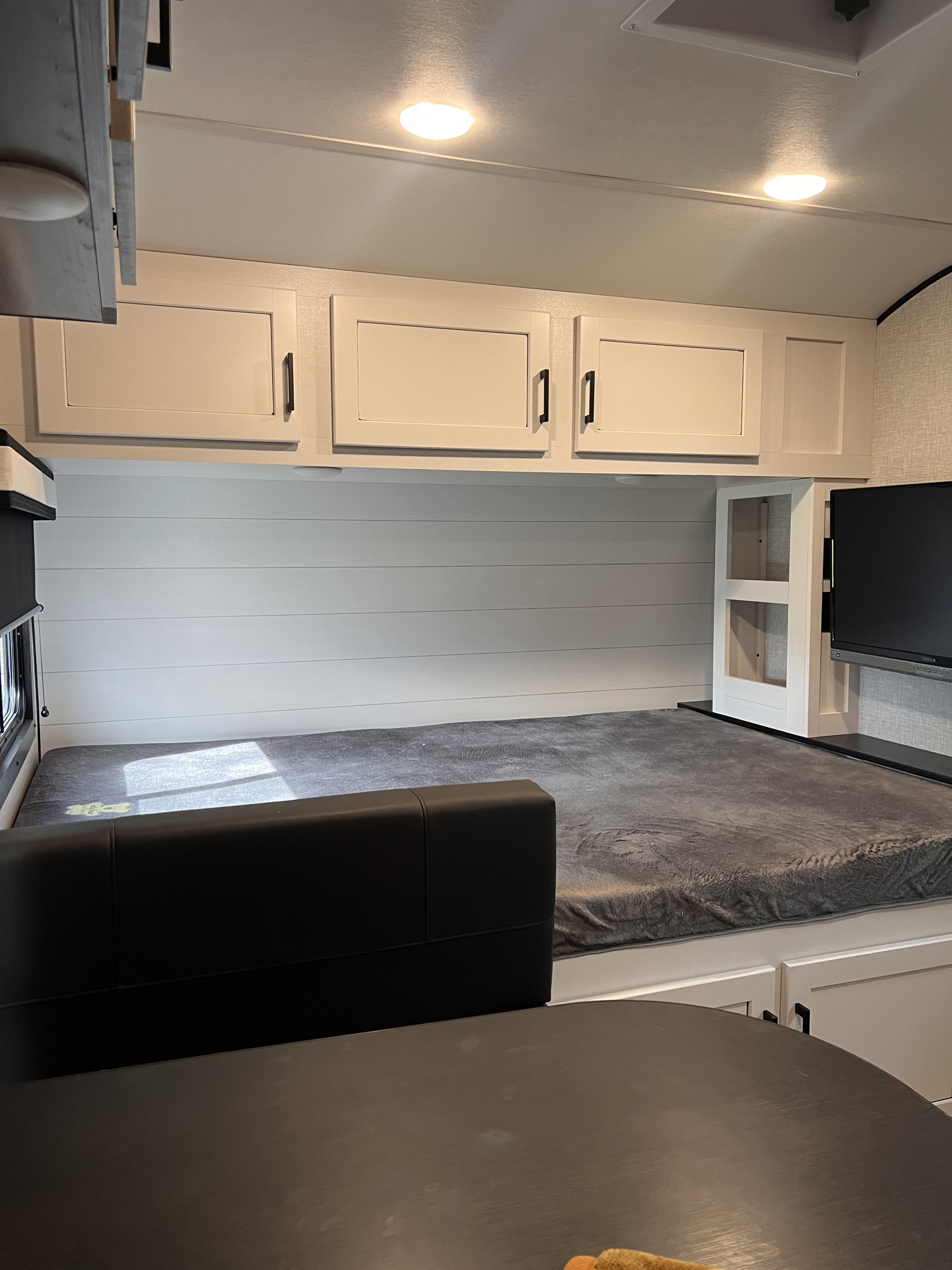Cozy RV rental bunk area with a comfortable bed, overhead cabinets, and a TV for entertainment.. Jayco Jay Feather Micro 2024