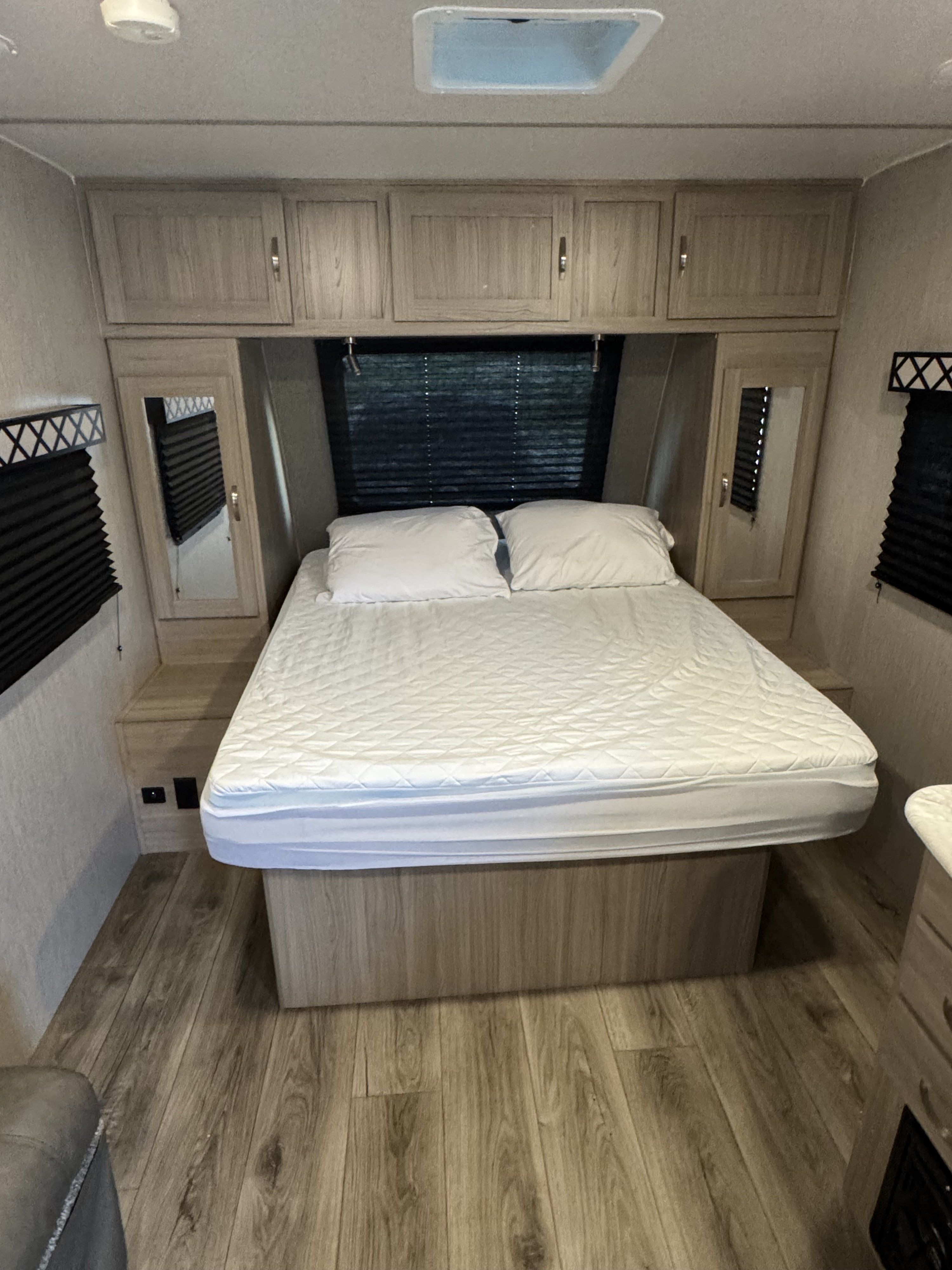 This RV rental bedroom features a comfortable full bed, overhead cabinets, mirrored wardrobes, and wood floors.. Coachmen Freedom Express 192RBS 2021