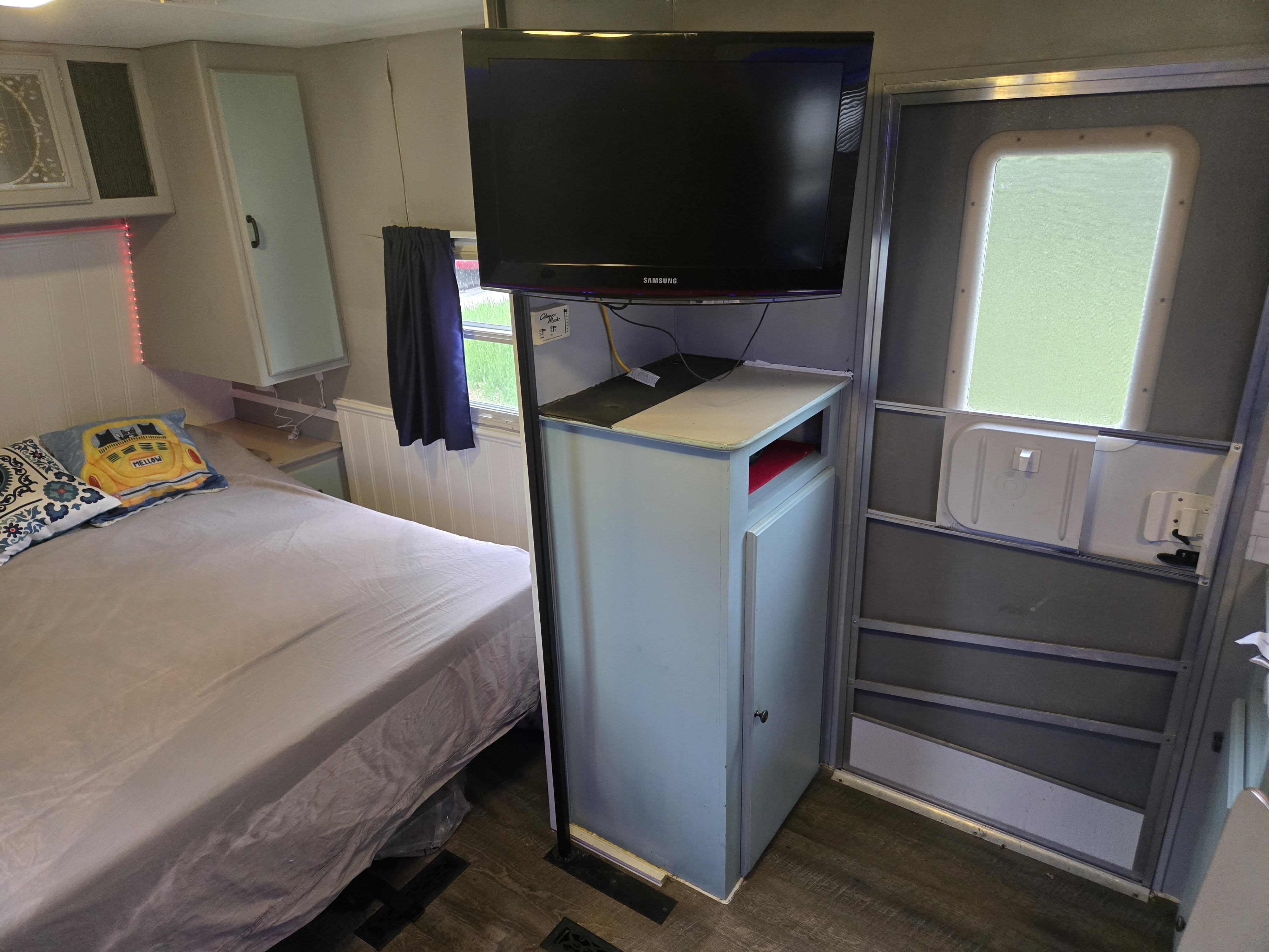 Cozy RV rental interior featuring a comfortable bed, wall-mounted Samsung TV, and built-in light blue cabinetry.. Fleetwood Mallard 2004