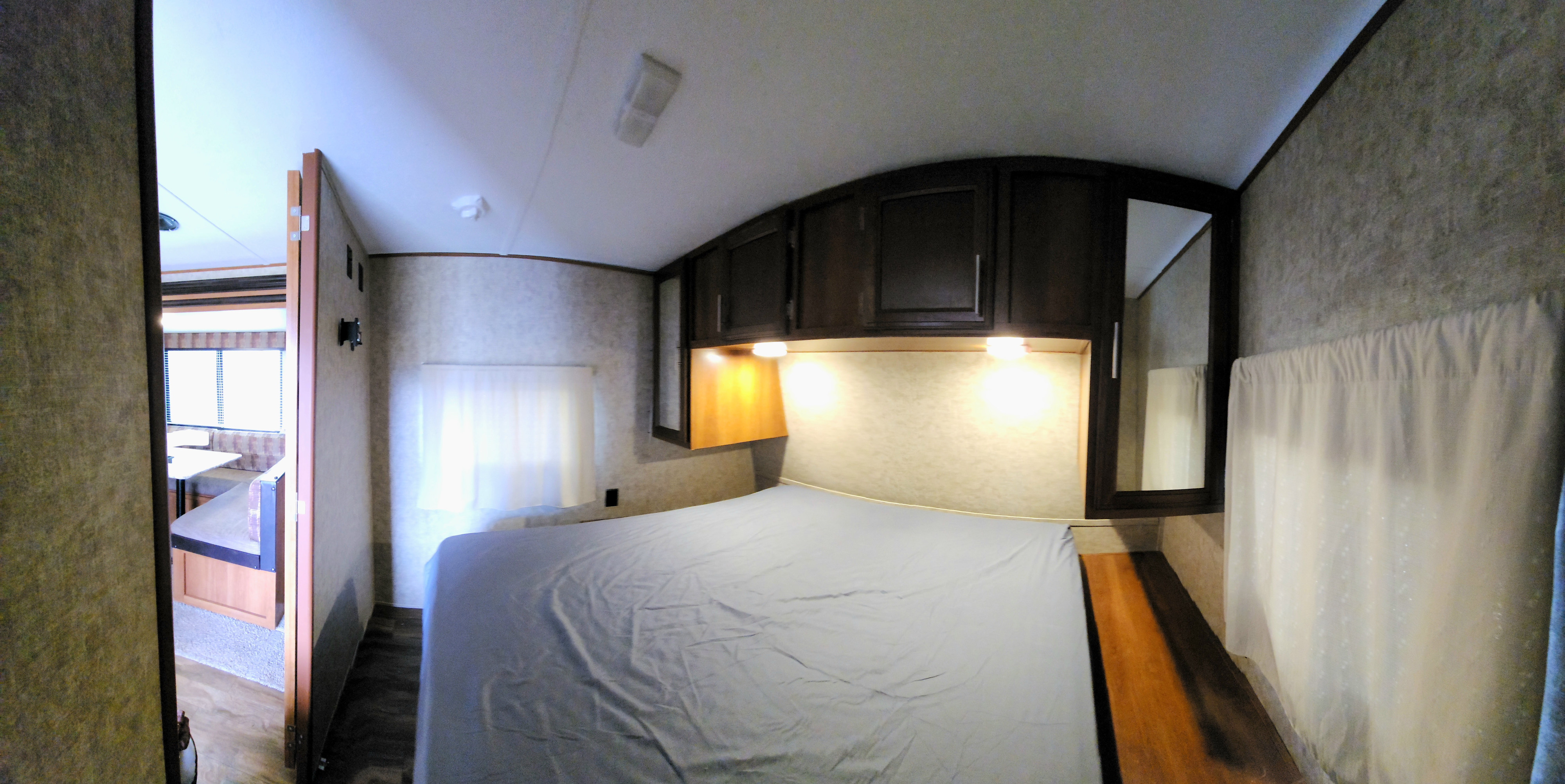 Experience our RV rental: A comfortable bedroom with overhead cabinets, leading to the dinette area. Perfect for your travel adventures.. Avenger ATI 2018
