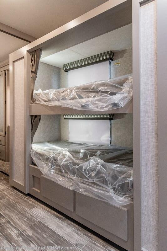 Inside this RV rental, two modern bunk beds are visible, with mattresses protected by plastic. Storage drawers are built-in below.. Thor Motor coach Geneva 2025