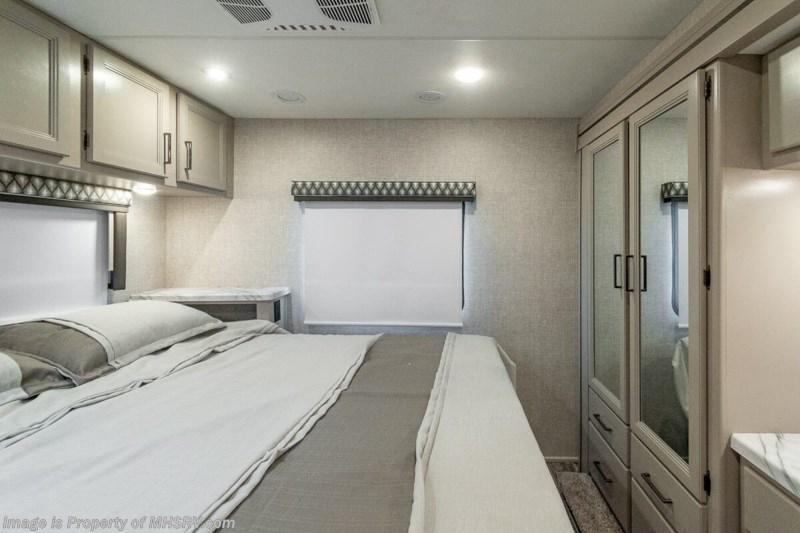 Spacious RV rental bedroom with cozy bed, overhead cabinets, window, and a full mirrored closet. Perfect for your trip.. Thor Motor coach Geneva 2025