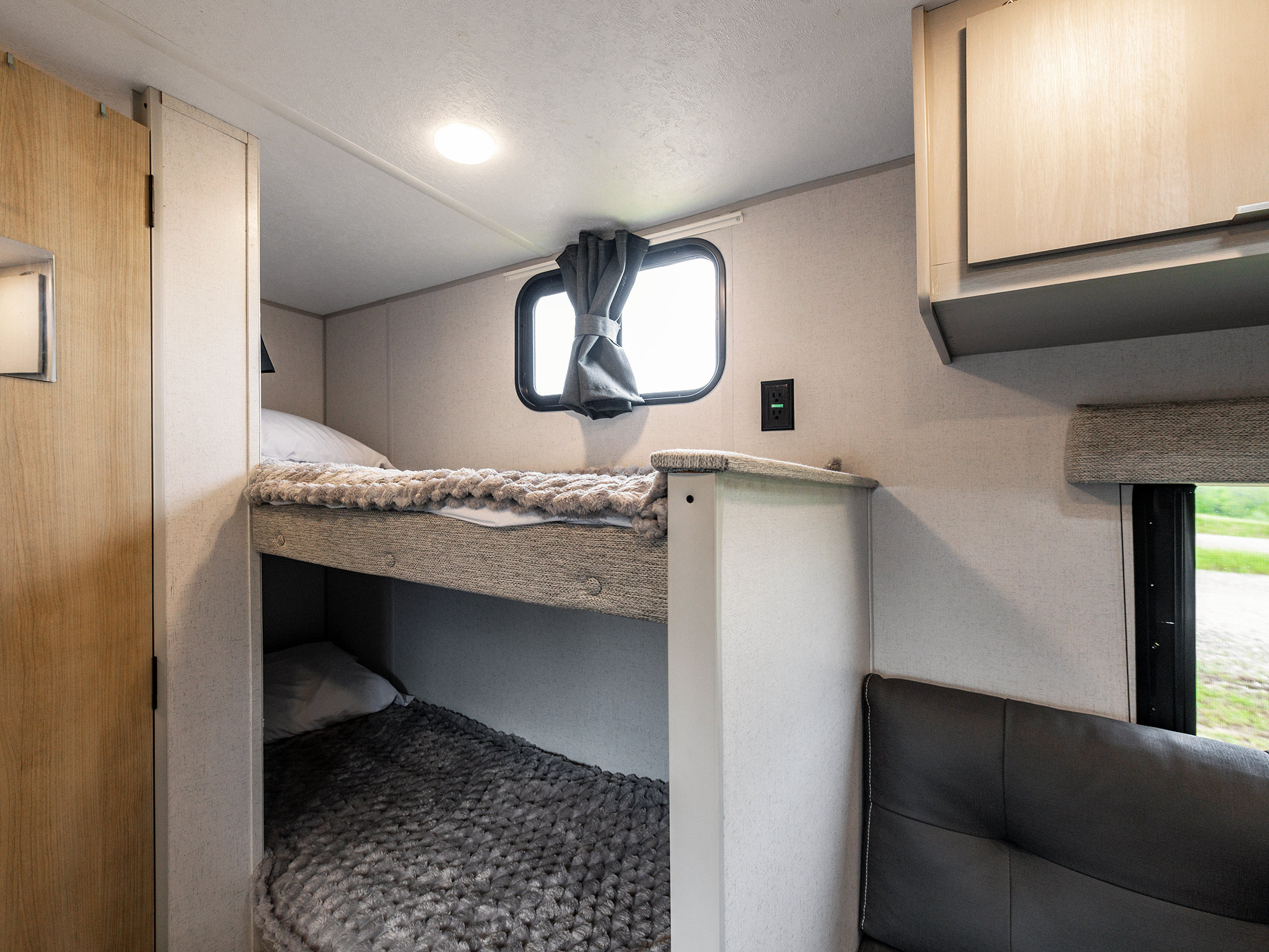 RV rental interior features brightly lit bunk beds, a window with privacy curtains, and a convenient power outlet.. Forest River Salem FSX 2023