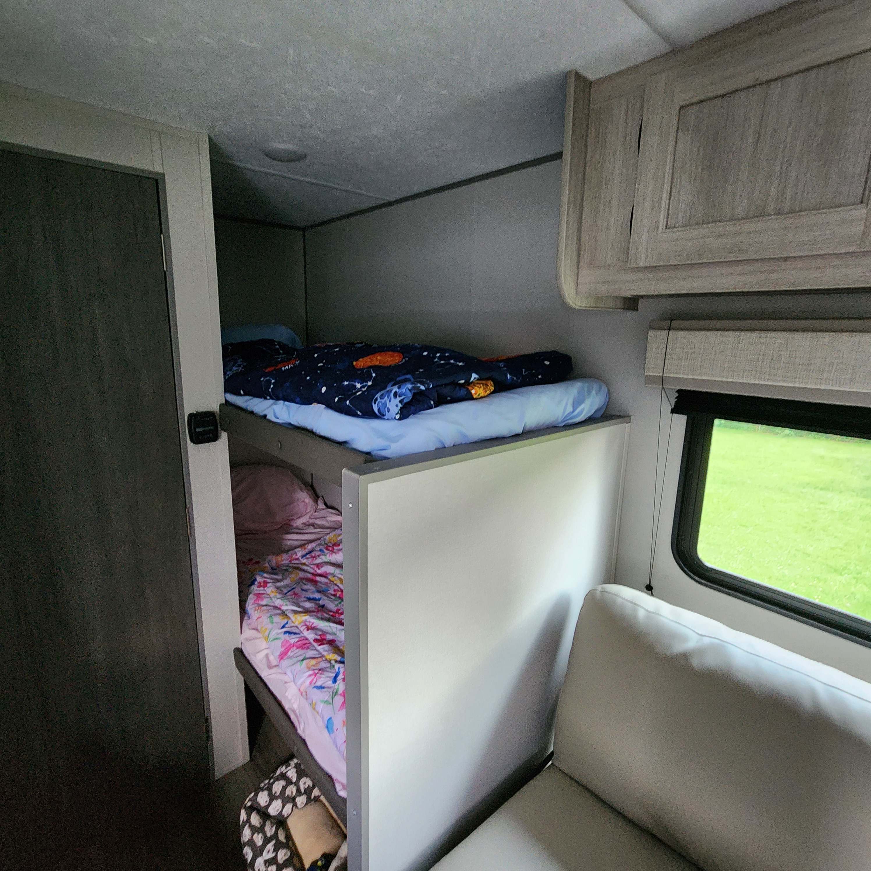 Inside an rv rental: comfortable bunk beds with colorful bedding and an exterior view from the window.. Coachmen Catalina 2024