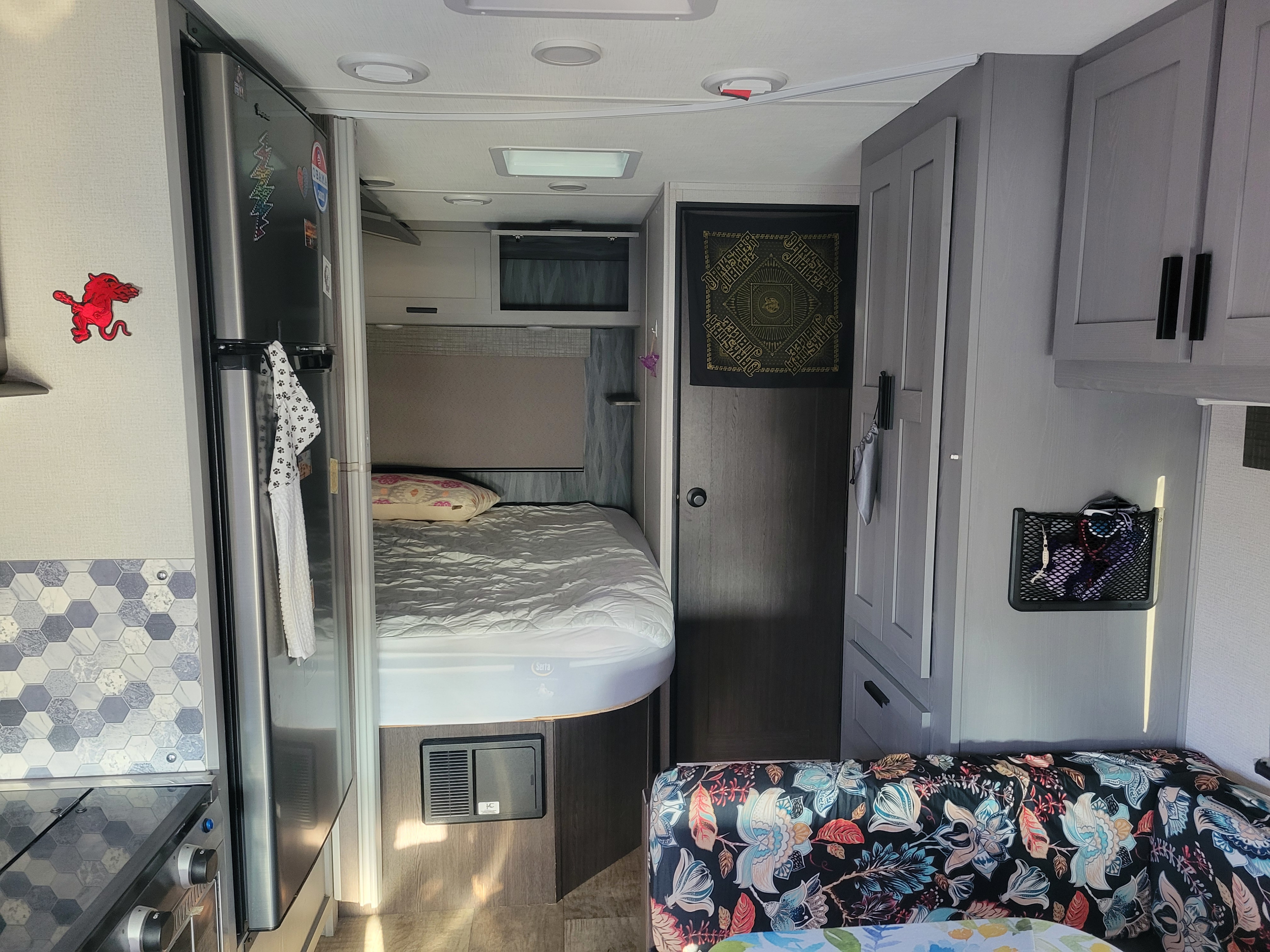 Experience comfort in this RV rental! Interior view shows a bed, kitchenette with hexagon tiles, and patterned seating area.. Solera Solera Motorhome 2022
