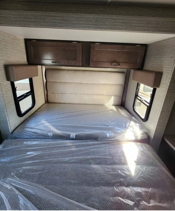 RV rental: Cozy sleeping area with new, plastic-covered mattresses, overhead storage, and side windows.. Winnebago Spirit 2024