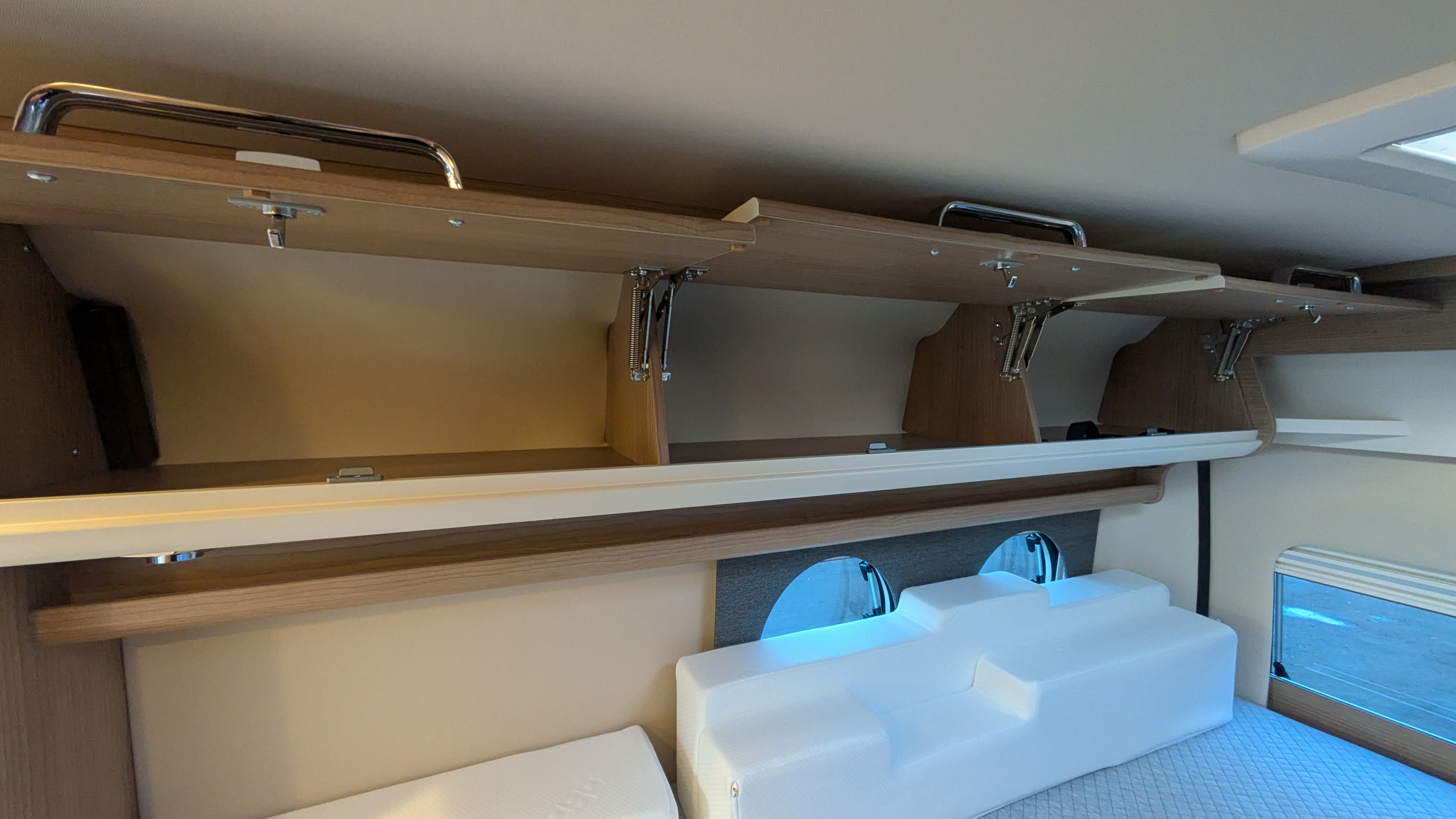 An RV rental's interior reveals open overhead cabinets with chrome handles, providing ample storage above the bed.. MALIBU 640 GB1ST CLASS 2 ROOMS 2025