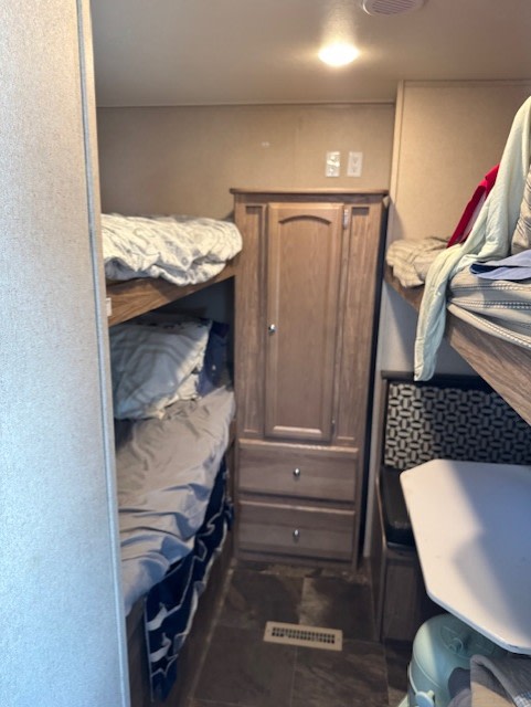 RV rental bunk room: narrow interior with stacked beds, a central wardrobe, and compact dinette. Cozy & functional.. Forest River Shasta Revere 2016