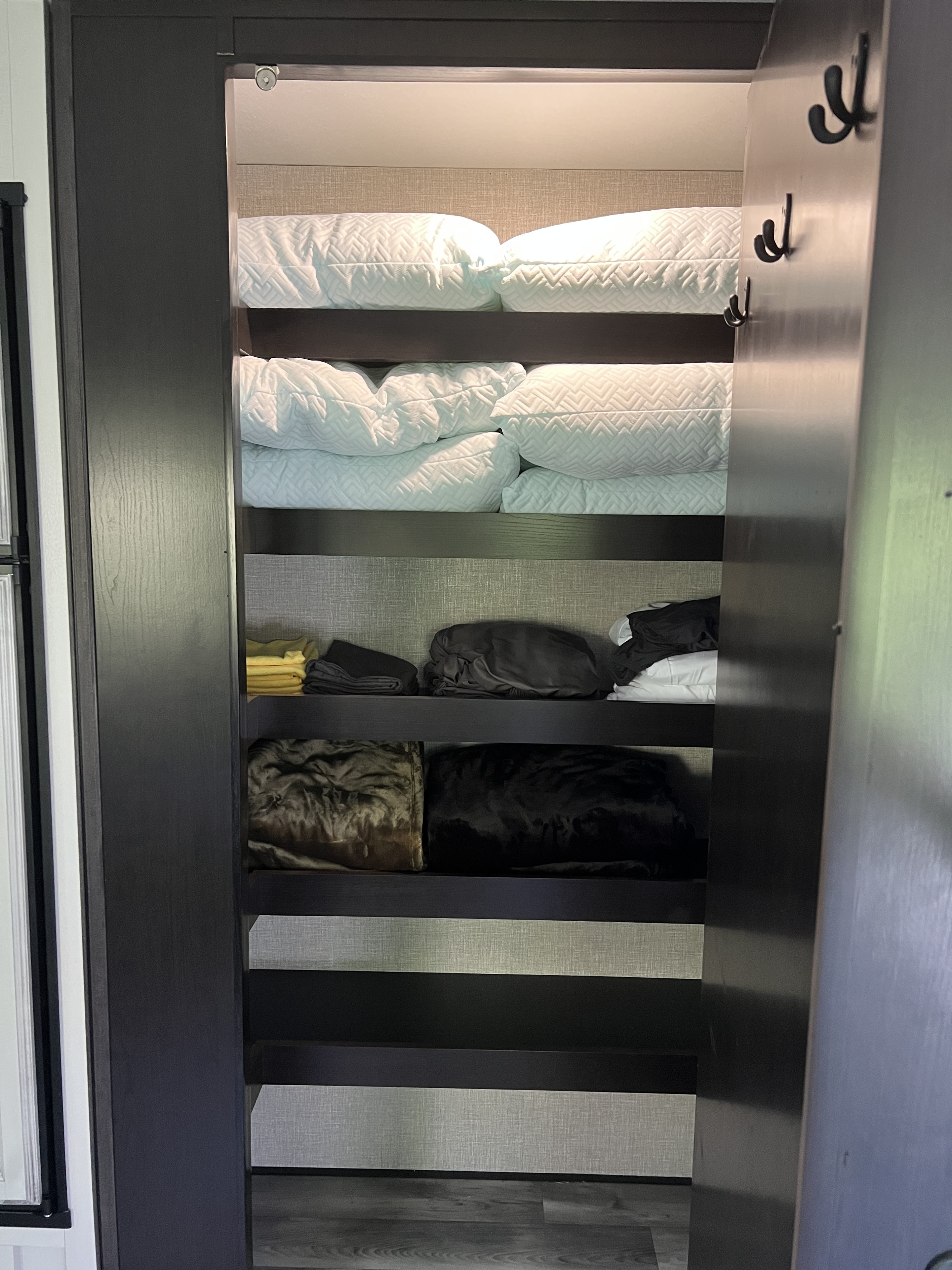 RV rental storage solution: White pillows & blankets on shelves, hooks on the door for a tidy space.. Jayco Eagle HT 2022