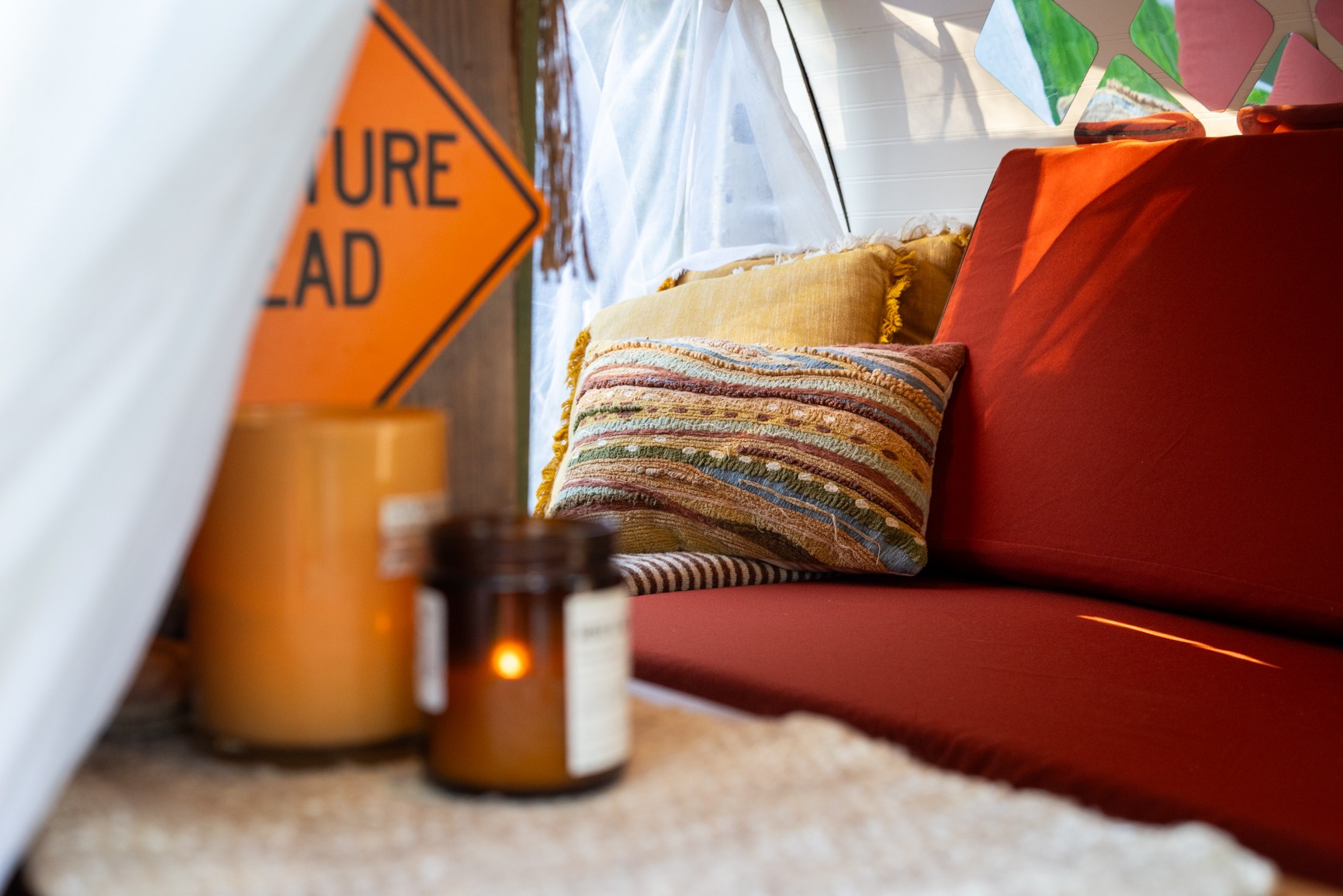 Warm & inviting RV rental interior: Red sofa, colorful pillows, and flickering candles create a cozy travel spot.. Ford Econoline 2012