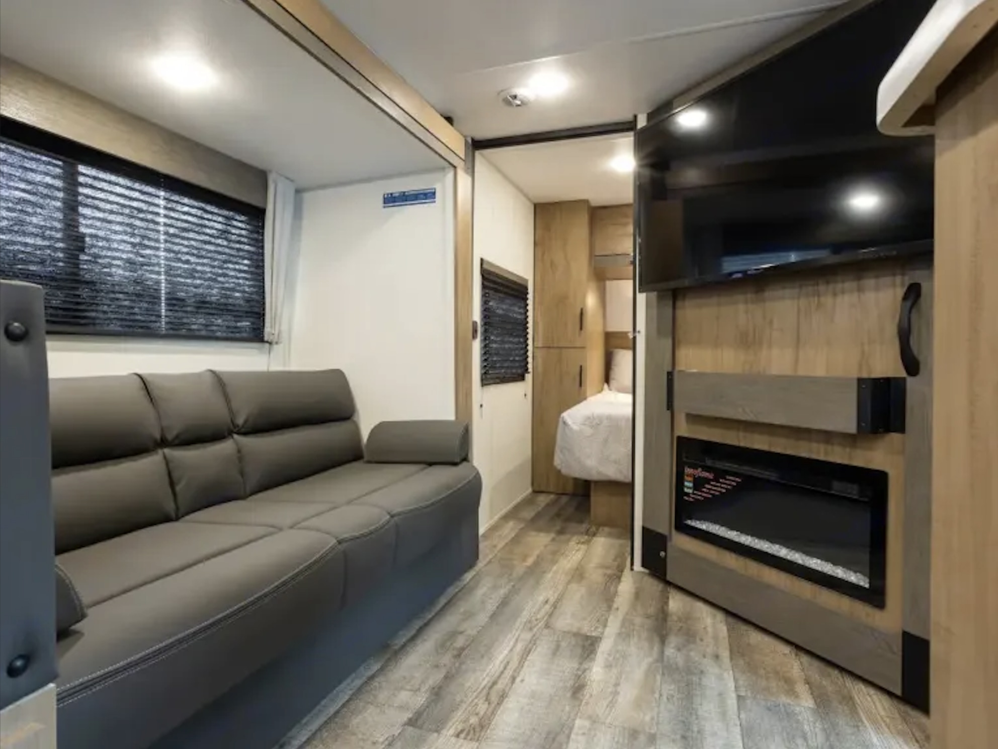 Tour this RV rental's cozy living area with a plush sofa, mounted TV, electric fireplace, and private bedroom.. 5ZT2CRRB4SF078661 26CJ 2025