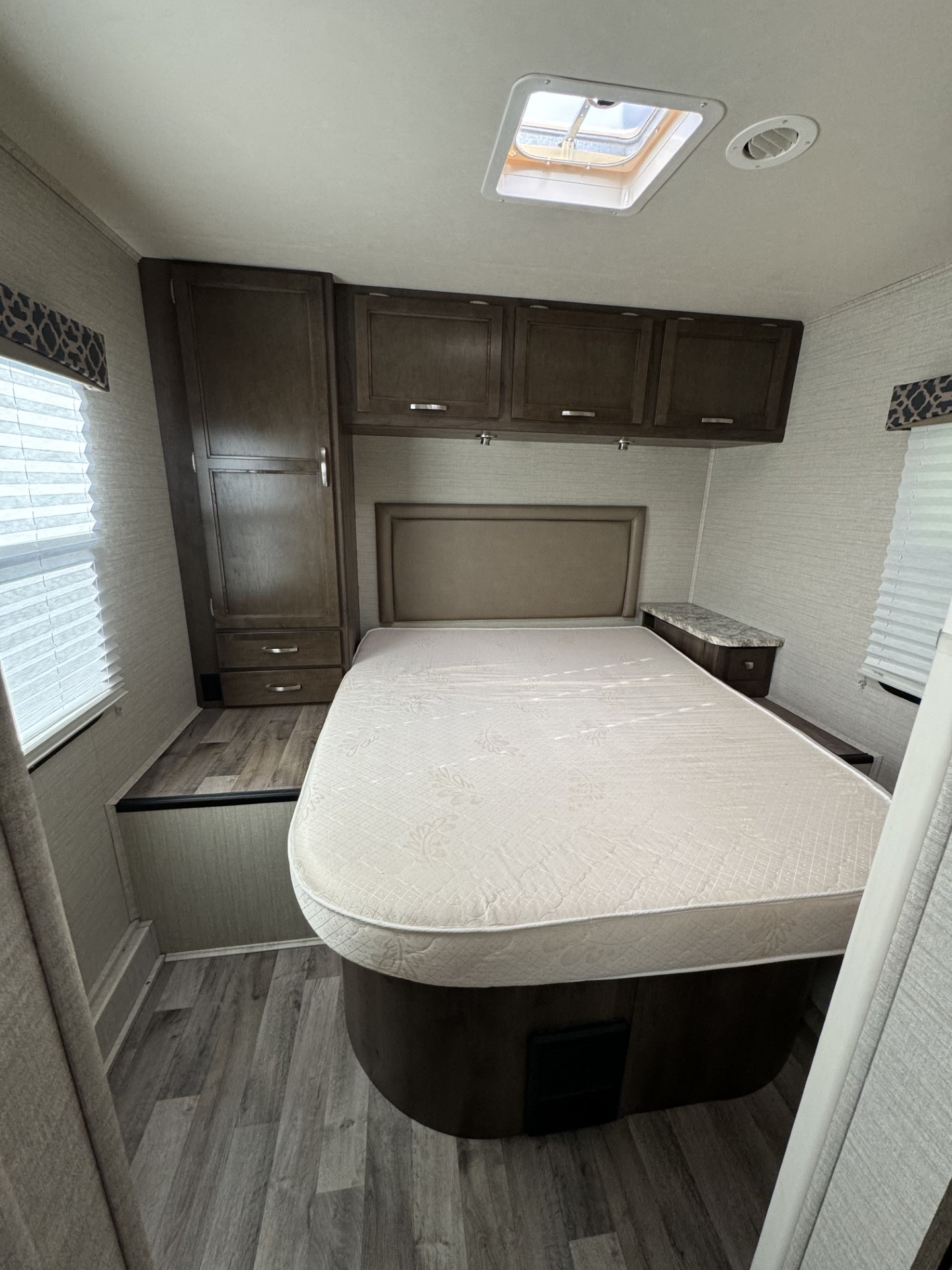 This RV rental bedroom has a bed, overhead cabinets, and a wardrobe, providing practical and comfortable lodging for your travels.. Jayco Redhawk 2019