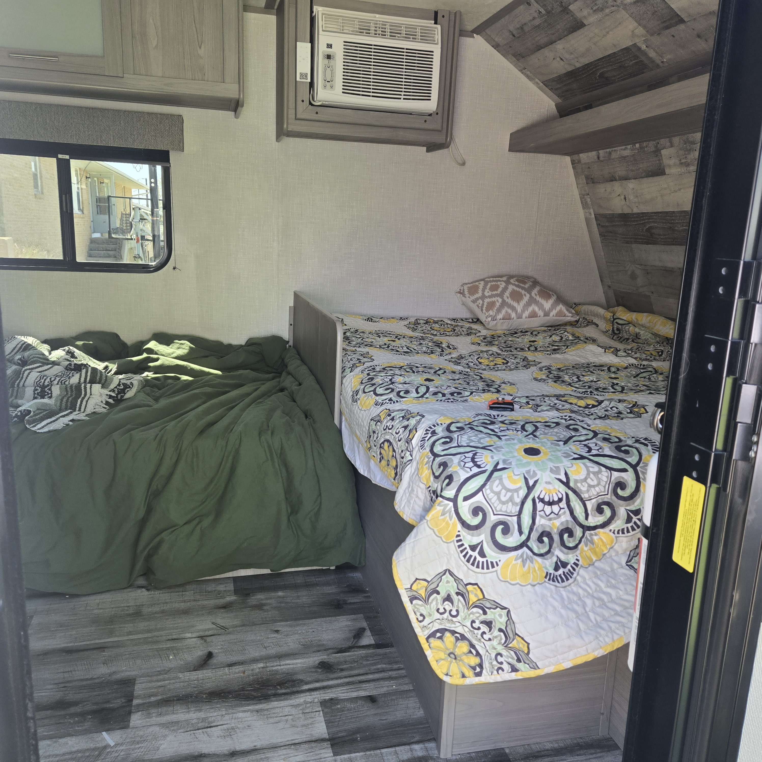 Cozy RV rental interior with two comfortable beds, AC unit, and scenic window view. Perfect for family adventures.. Dutchmen Coleman Lantern LT 2023