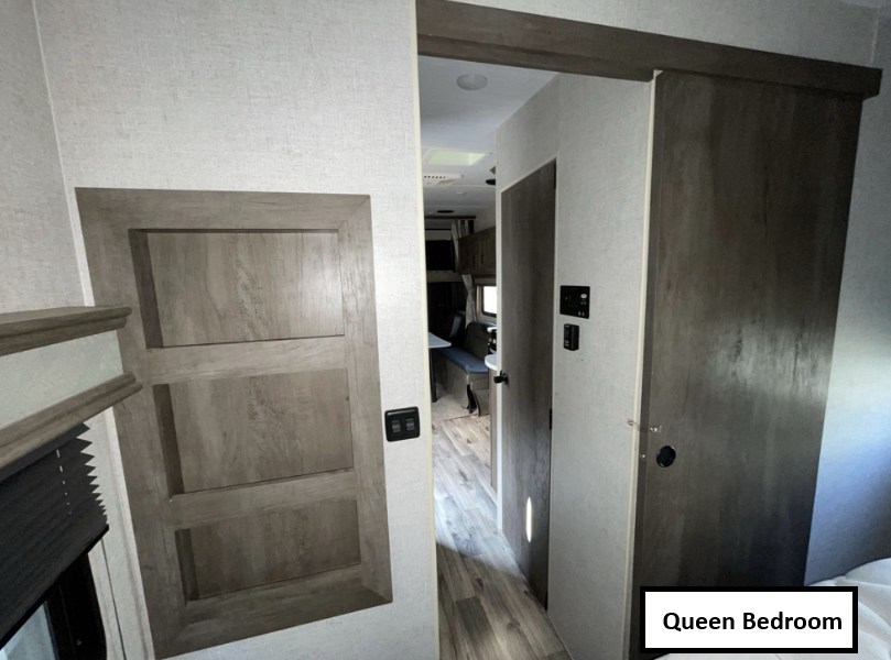 RV rental interior: View from the queen bedroom showing built-in storage, and a sliding door leading to the living area.. Forest River Shockwave 2021