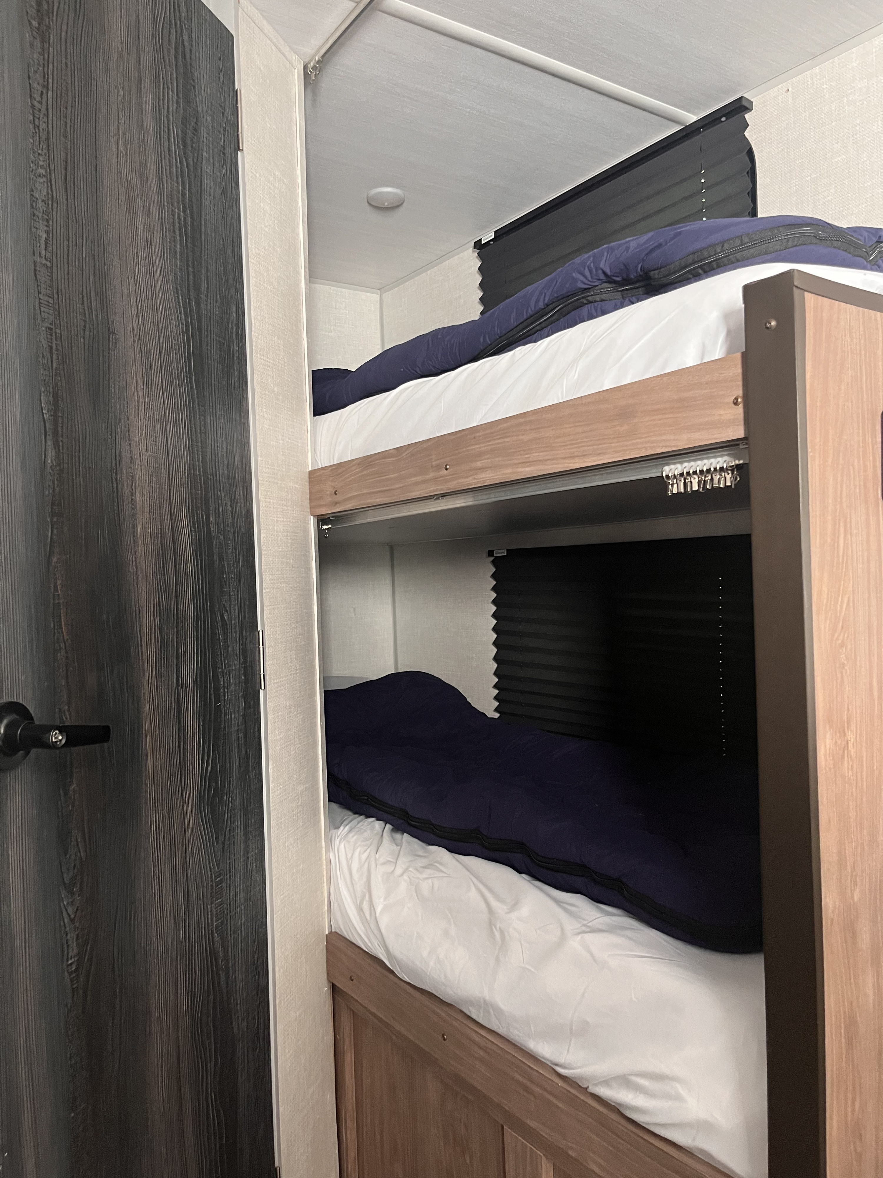 RV rental interior featuring two comfortable bunk beds with white sheets, dark bedding, and privacy blinds.. Forest River No Boundaries ( NO BO ) 19.8 2022