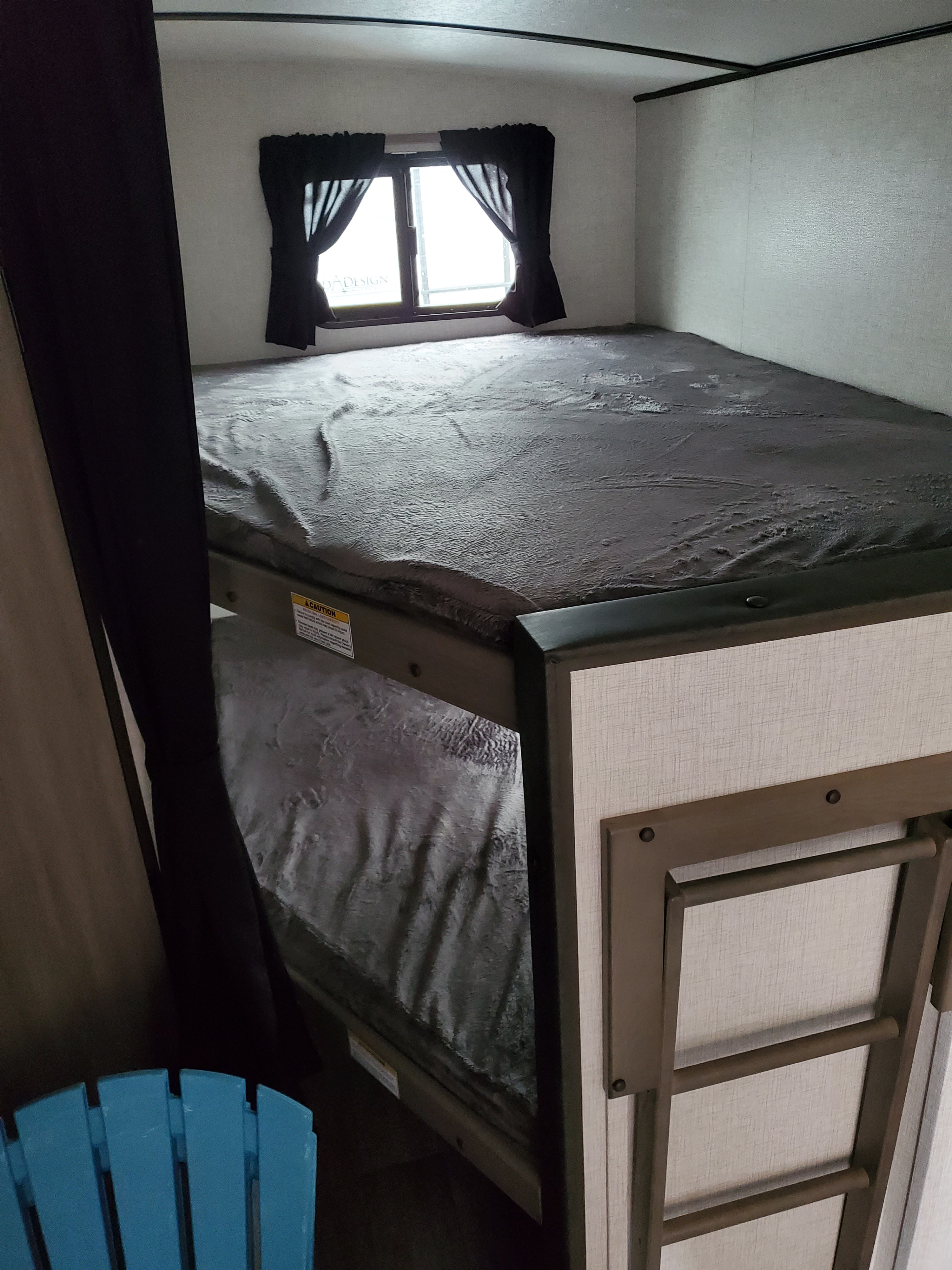 RV rental interior: two cozy bunk beds with a window and a folded ladder, perfect for family sleeping in a camper.. Crossroads Sunset Trail Super Lite 2021