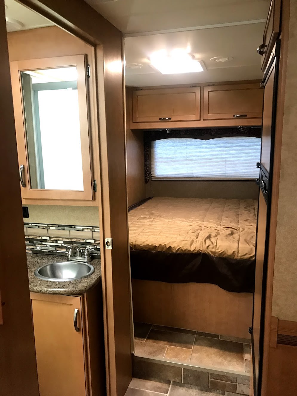 RV rental: View of compact interior with bathroom sink area on left and cozy bedroom with bed and cabinets on right.. Thor Four Winds 2016