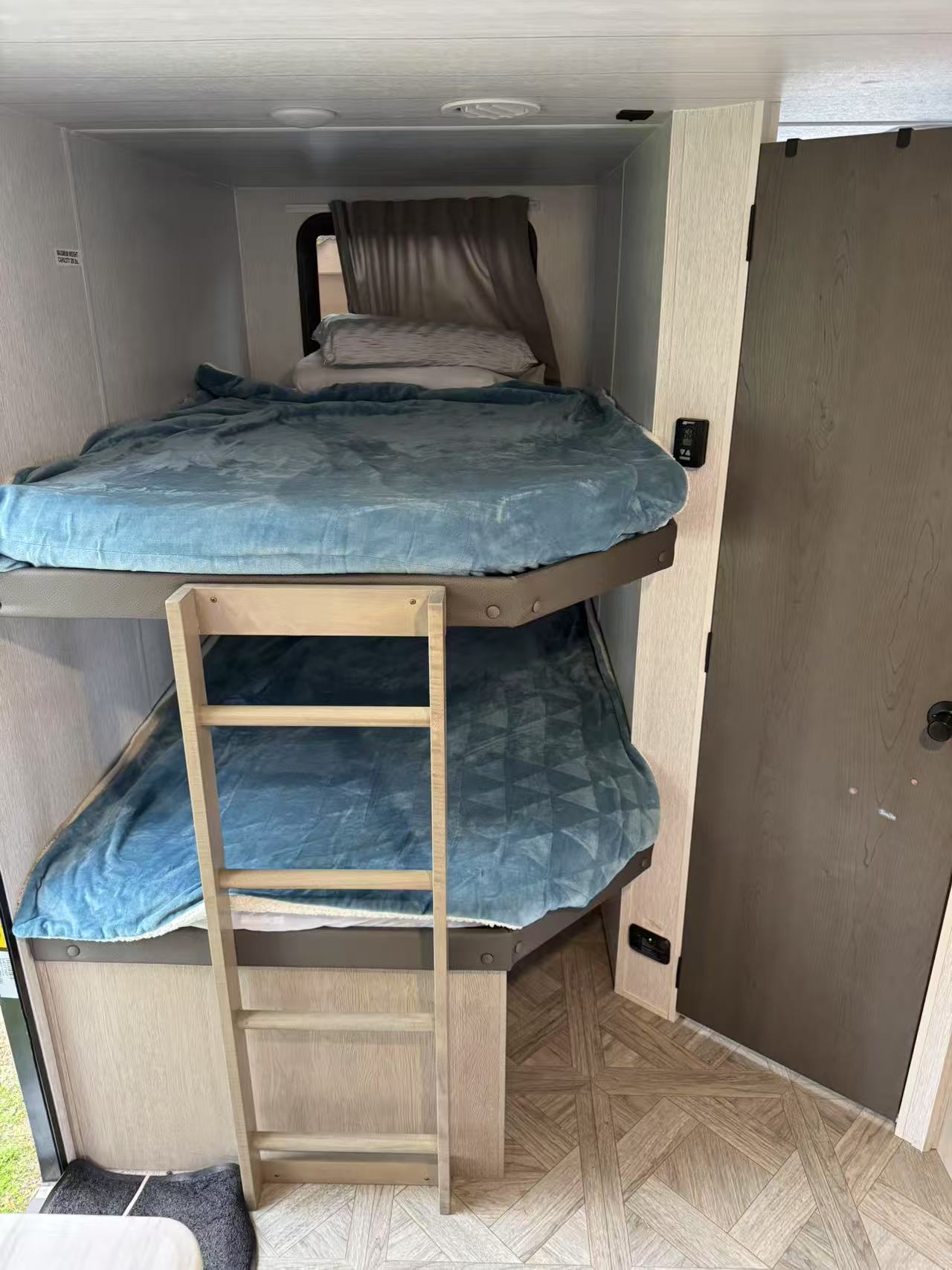Inside an RV rental: two comfy bunk beds with blue blankets and a ladder for access. Ideal for family adventures.. Forest River EVO 2024