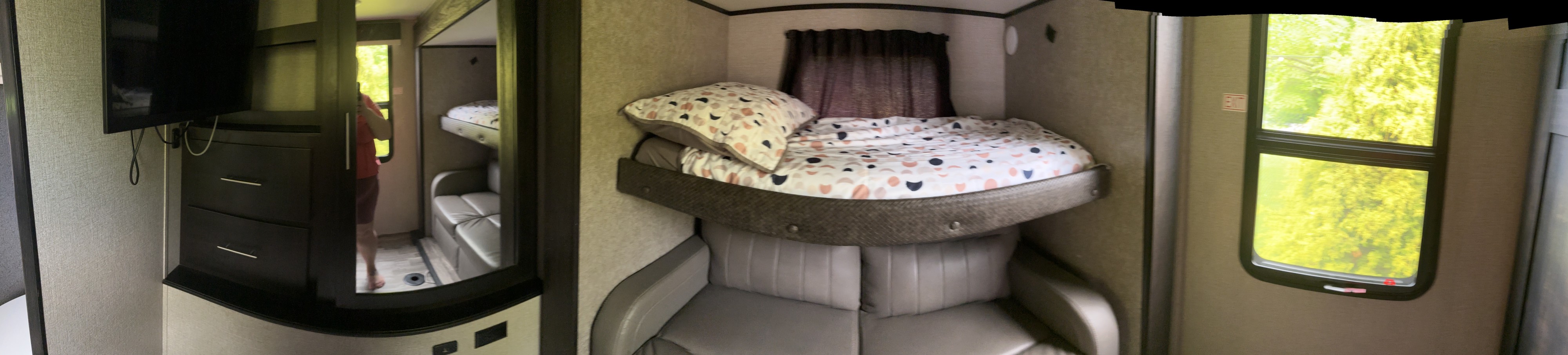 Inside an RV rental: bunk beds over a comfy couch, plus a TV & window view. Compact camper living.. Jayco North Point 2021