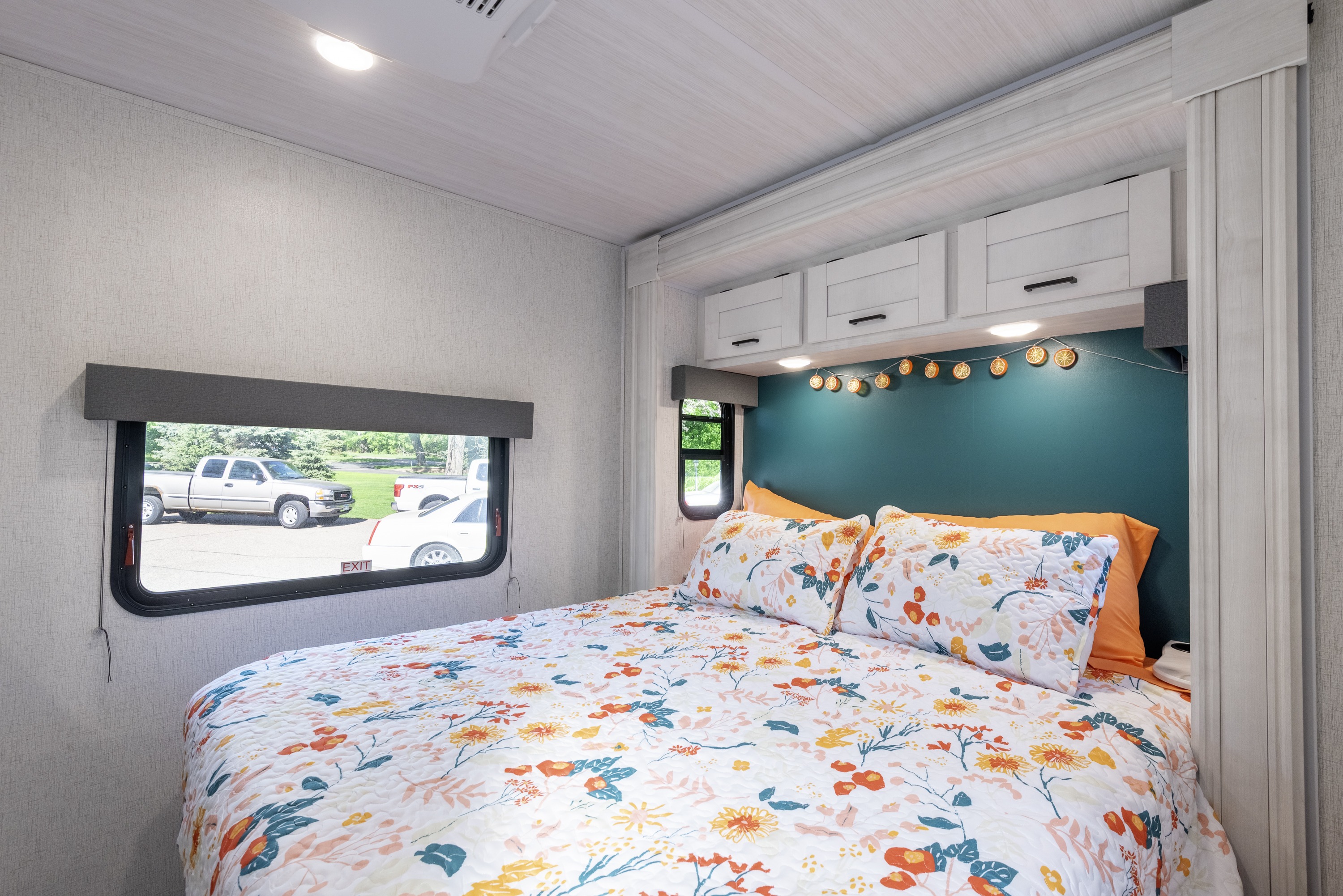 Cozy RV rental bedroom with colorful floral bedding, a teal accent wall, and practical overhead storage.. Entrada Entrada Motorhome 2022