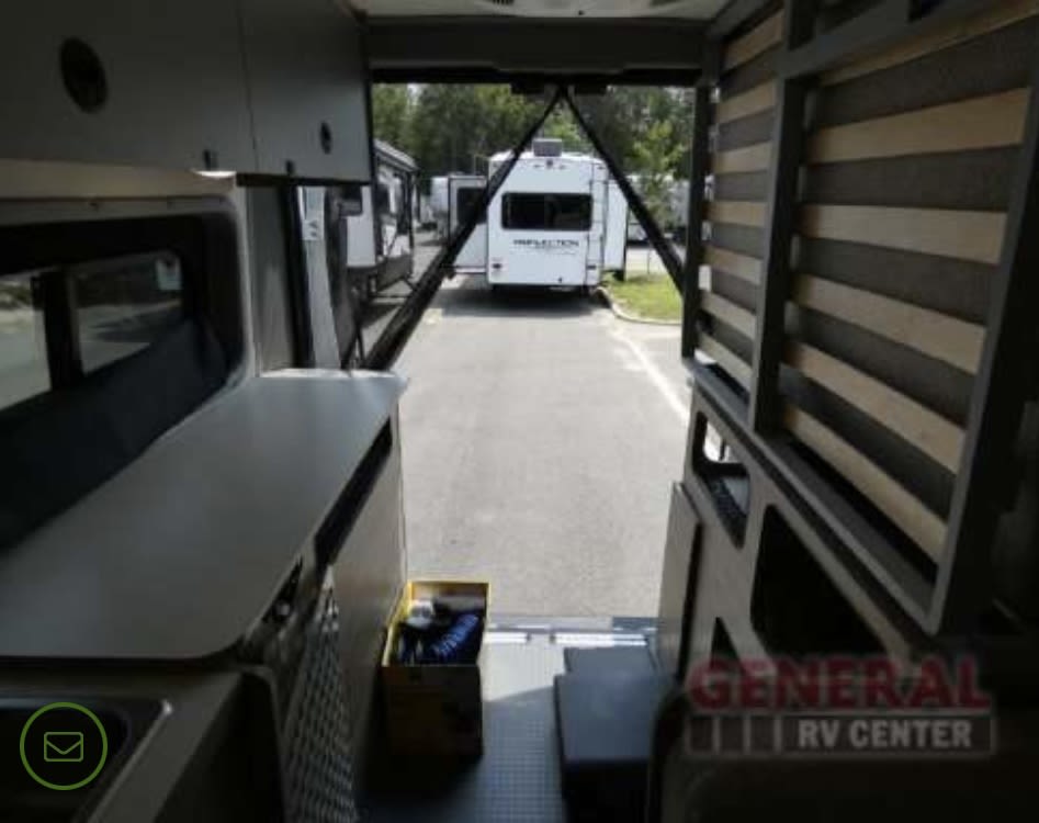 RV rental interior view: large cargo area, versatile fold-up bed, and kitchenette visible. Ready for your trip!. Winnebago Solis 2023
