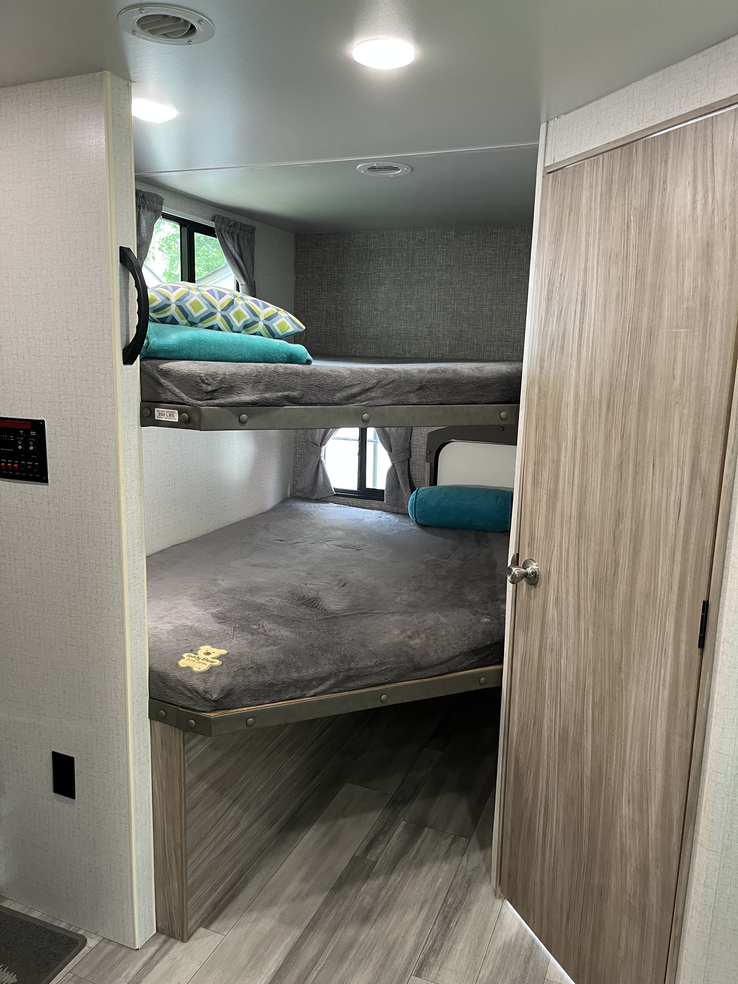 Cozy bunk beds in an **rv rental**, featuring soft grey blankets and pillows. Perfect extra sleeping space inside an RV.. Winnebago Minnie Winnie 2022