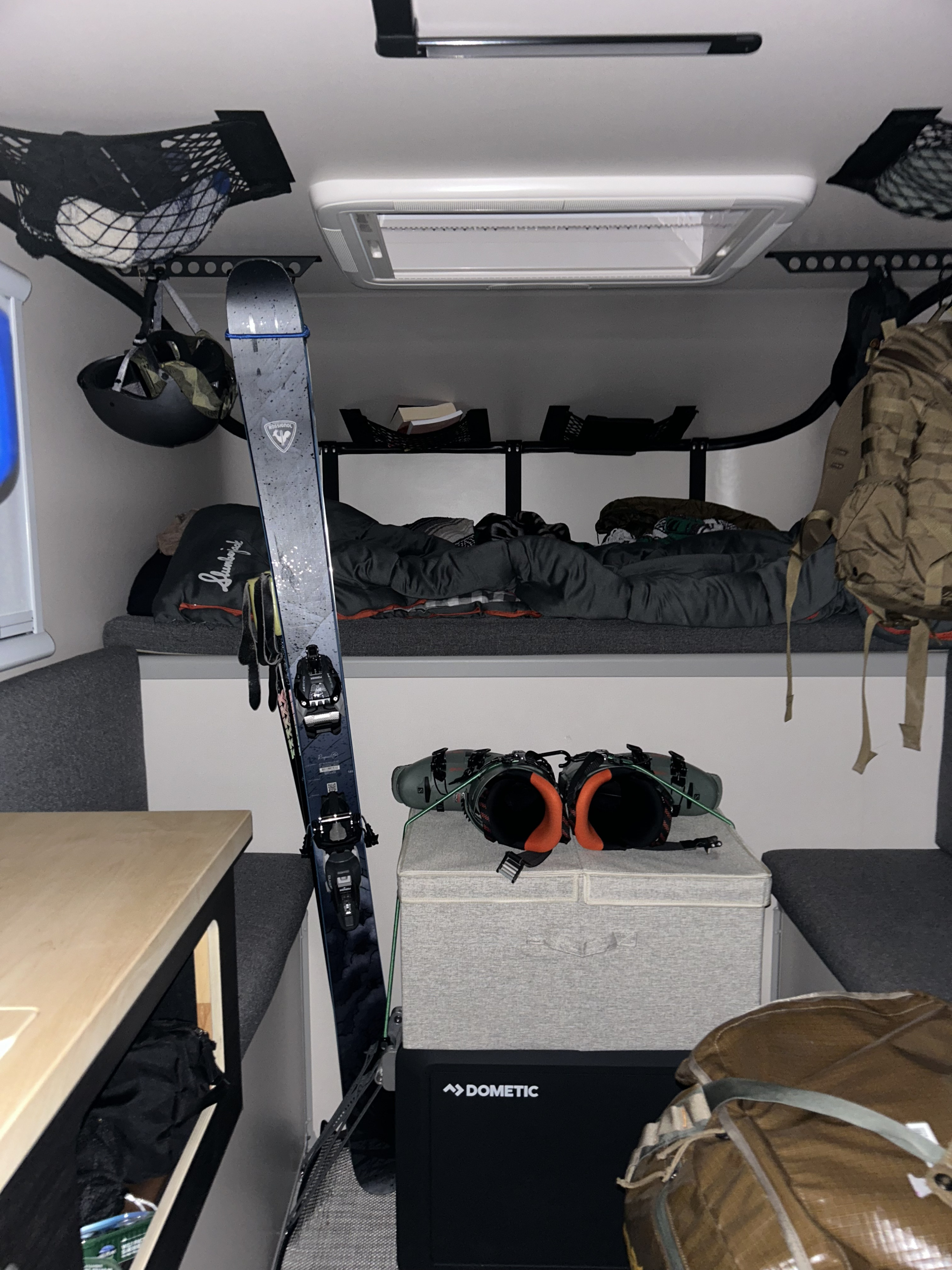 Inside a compact RV rental: skis, boots, and gear for winter adventures, with a cozy bed and Dometic cooler.. Toyota Tacoma 2018