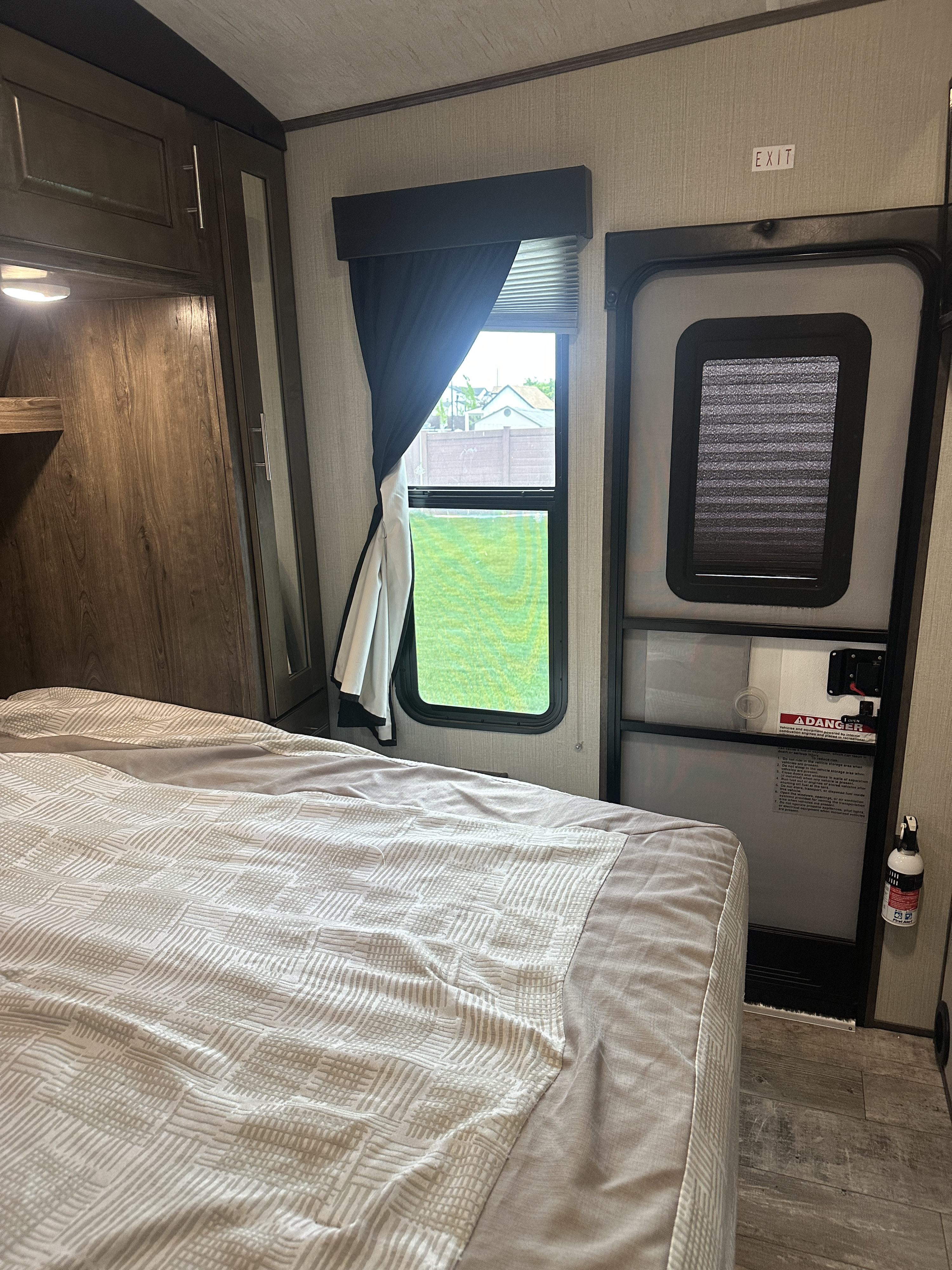 RV rental: Bedroom with a comfortable bed, window overlooking grass, and an exit door with a visible fire extinguisher.. Heartland Torque 2018