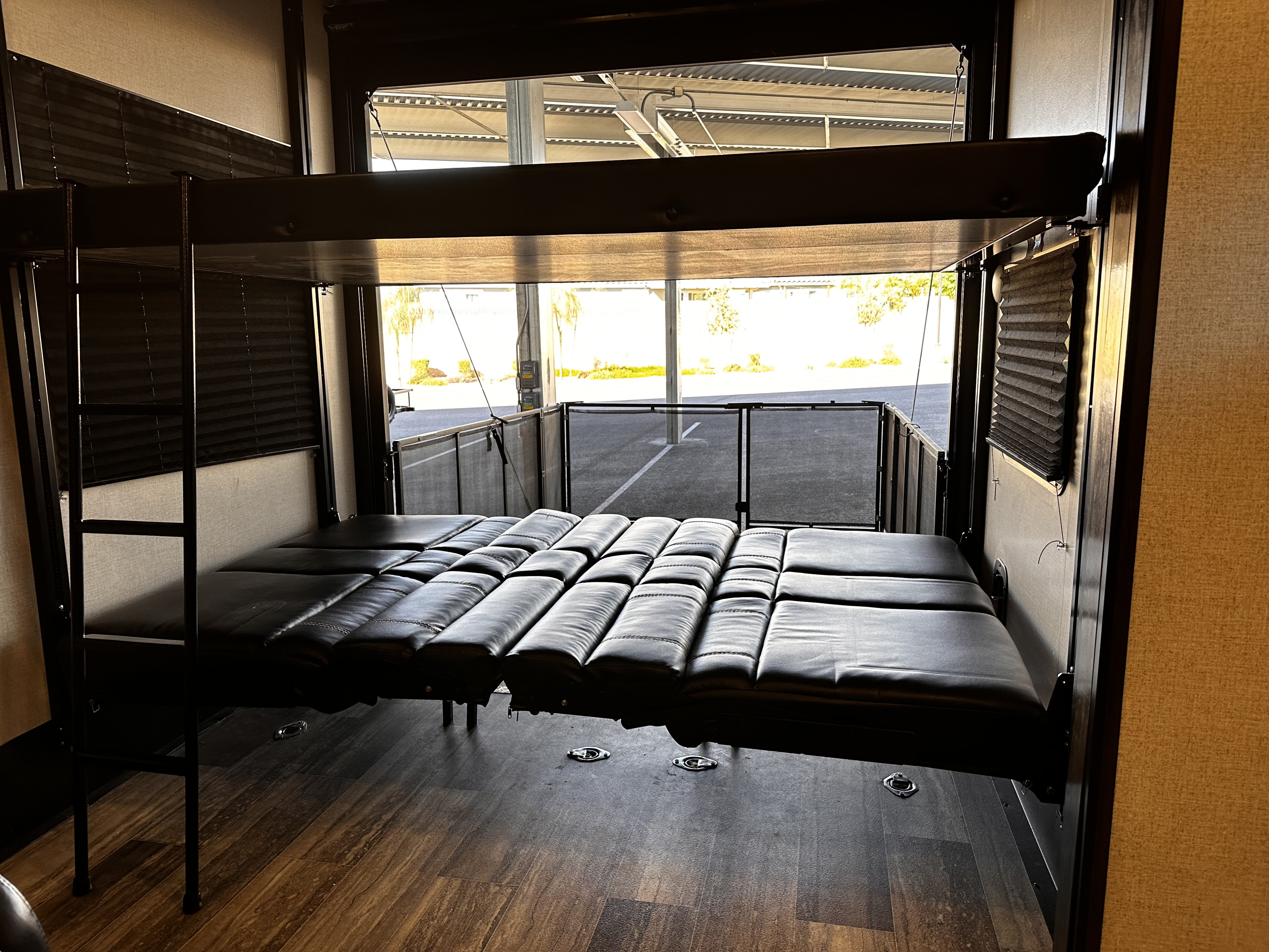 Spacious RV rental interior with convertible bunk beds and rear ramp open to a concrete lot, featuring floor tie-downs.. Dutchmen 3351 2022