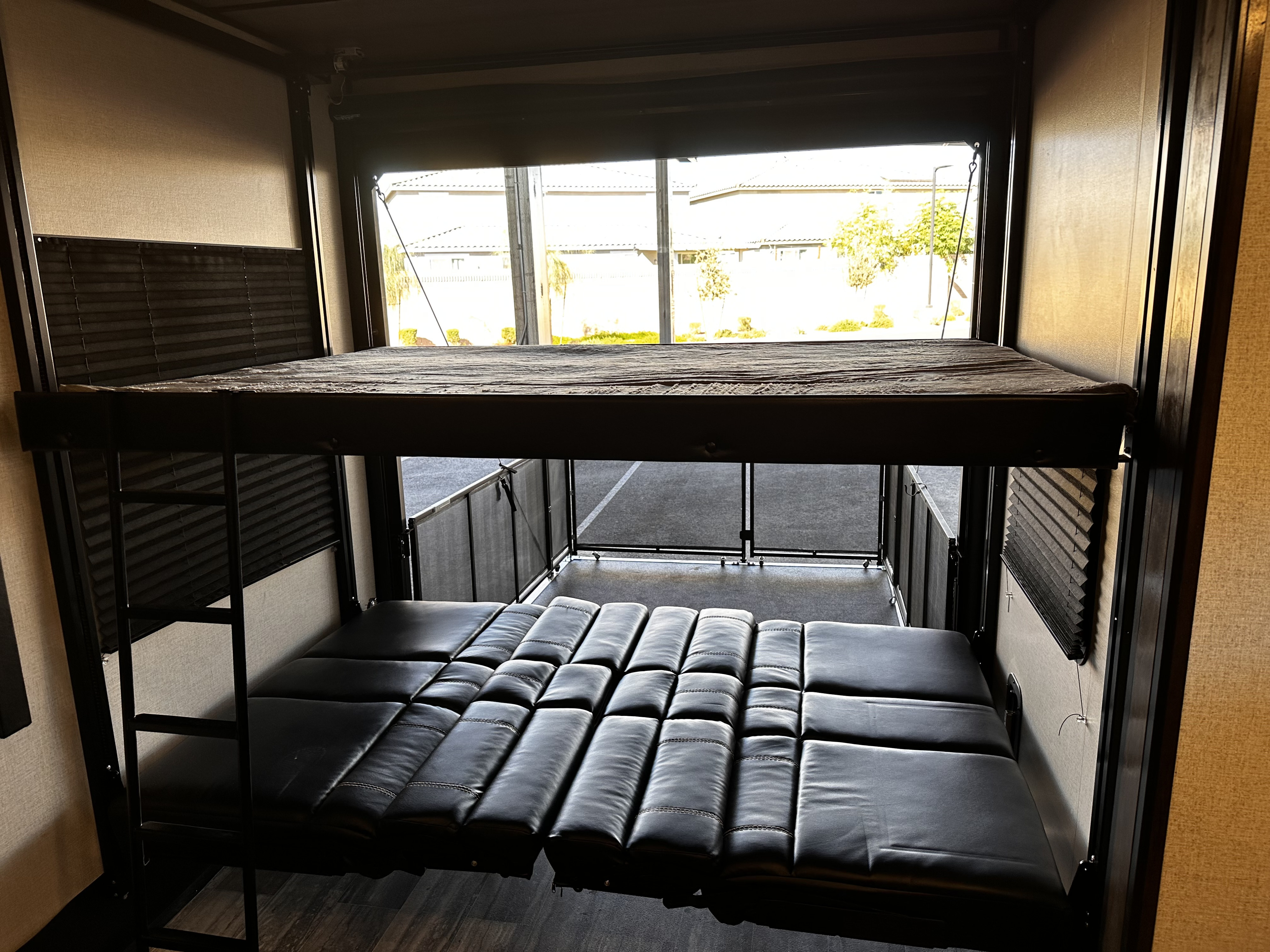 This RV rental features a toy hauler garage with stacked bunk beds and convertible seating, seen through its wide-open rear.. Dutchmen 3351 2022