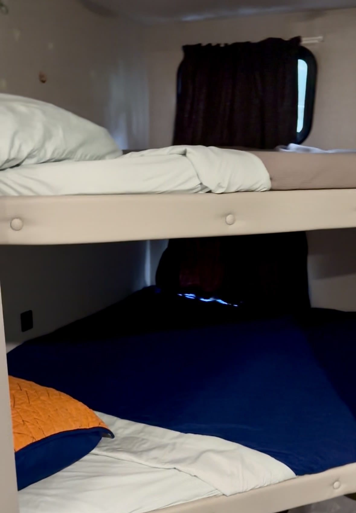 An RV rental interior shows cozy bunk beds with light and dark blue bedding, offering comfortable travel accommodations.. Forest River Ozark 1680 BSK 2021