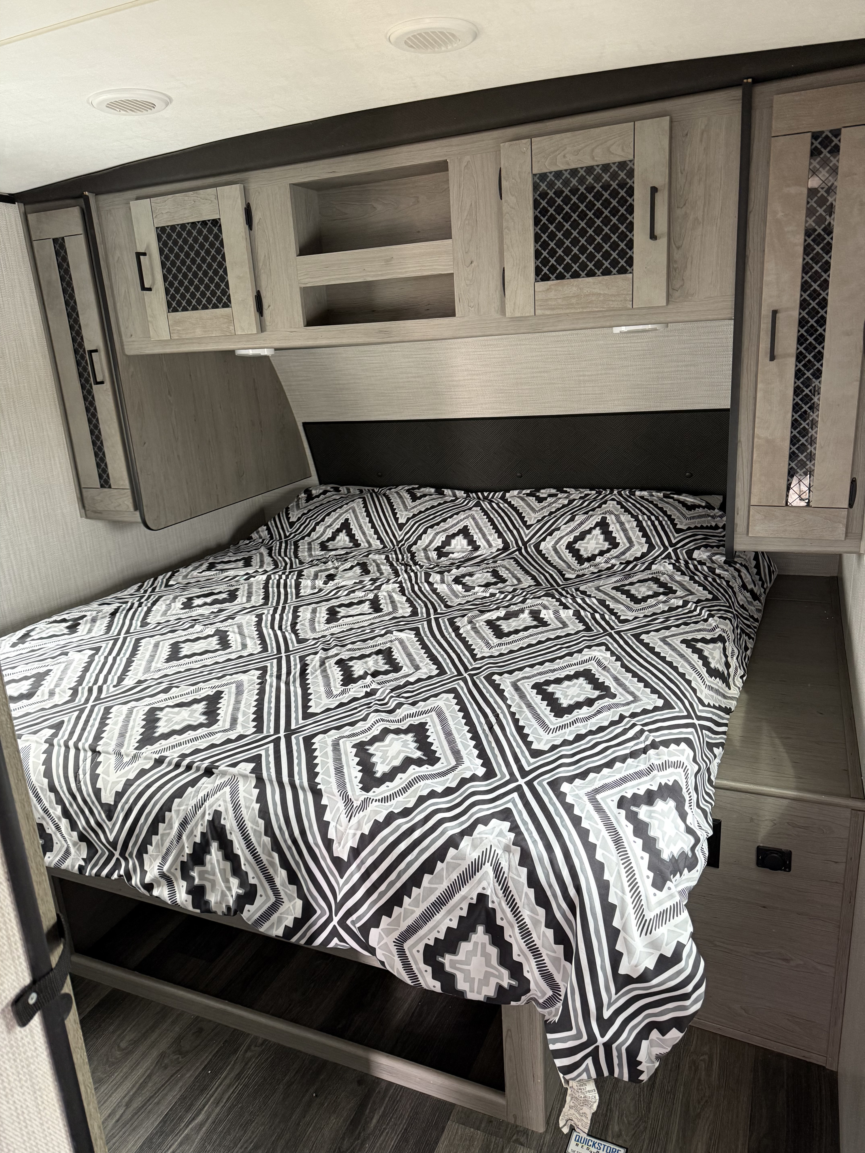 RV rental bedroom view: patterned bed, integrated headboard, and functional overhead cabinets.. Heartland RVs Mallard 2021