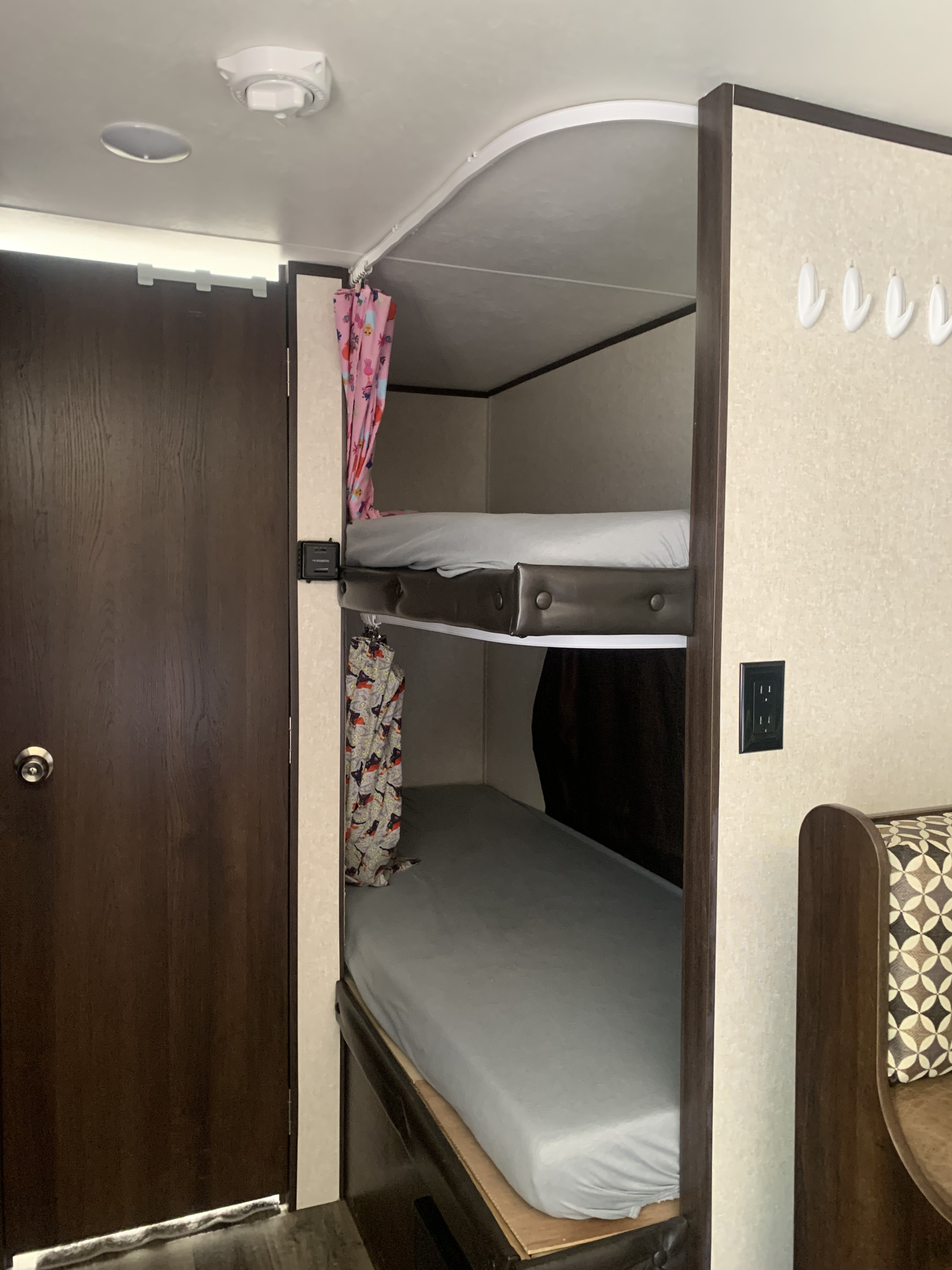 View inside an RV rental, showing a cozy sleeping area with two bunk beds, colorful curtains, and a compact design.. Jayco Jay Flight SLX 2019