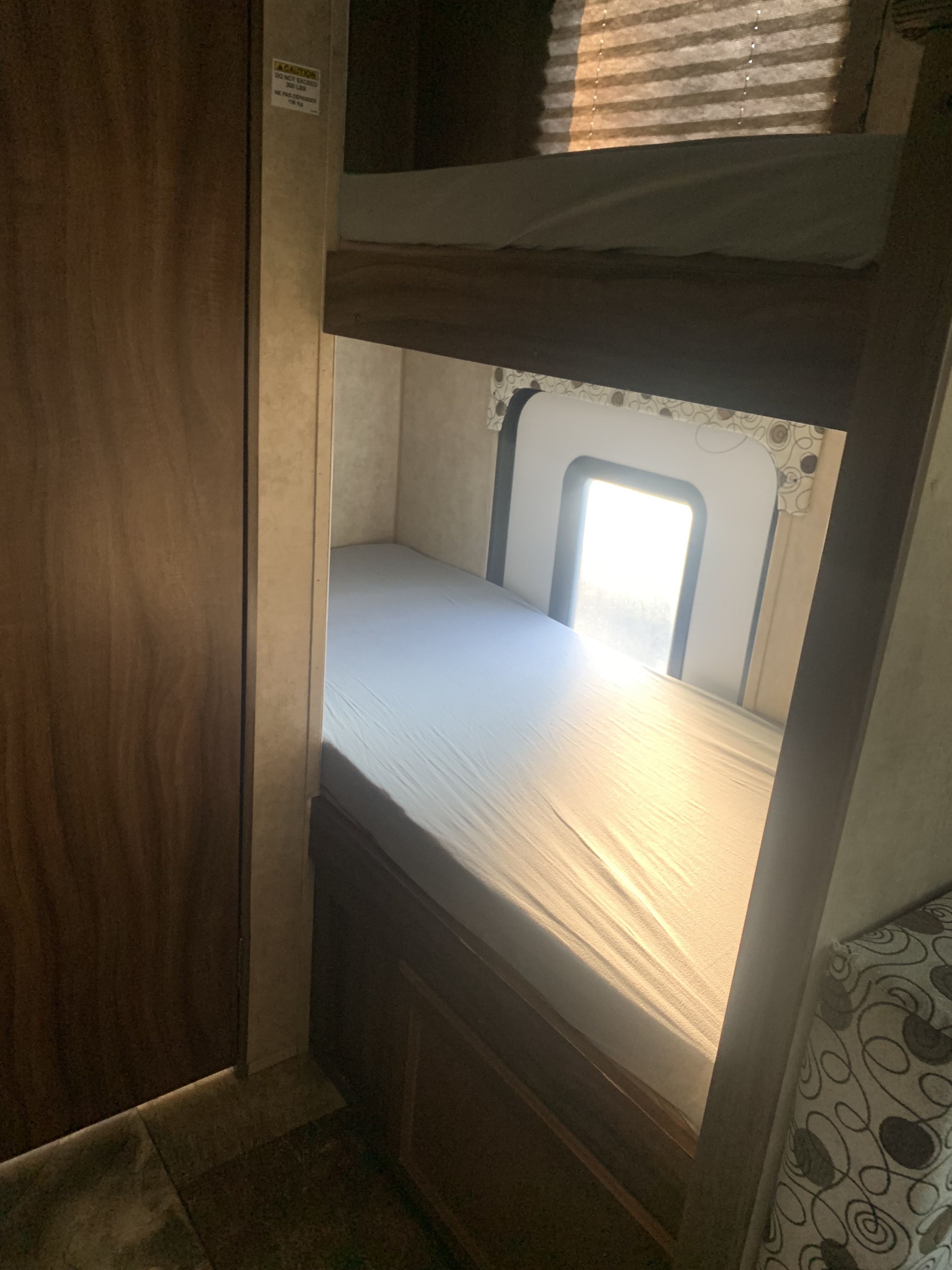 Cozy RV rental bunk beds bathed in sunlight, offering comfortable sleeping in a camper interior.. Coachmen Clipper ultra lite 2017