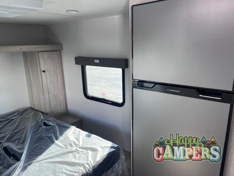 RV rental bedroom with a covered bed, built-in cabinet, window, and modern Furrion refrigerator. Perfect for travel!. Riverside RV Intrepid 2023