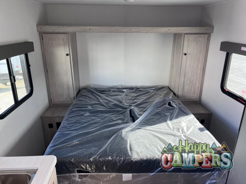 Inside an RV rental: a cozy bedroom with a protected bed, bedside cabinets, and overhead storage. Ready for your next journey.. Riverside RV Intrepid 2023