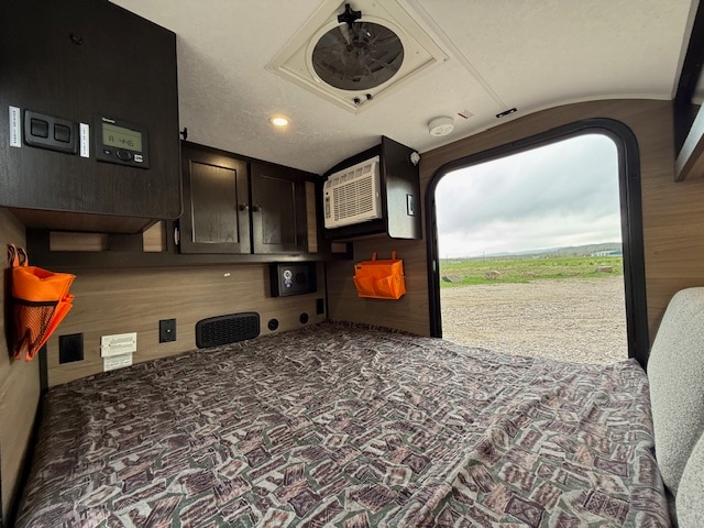 RV rental camper interior: a compact bedroom with controls, AC, and an open door offering an outdoor view.. Braxton Creek Bushwhacker 10HD Radical 2024