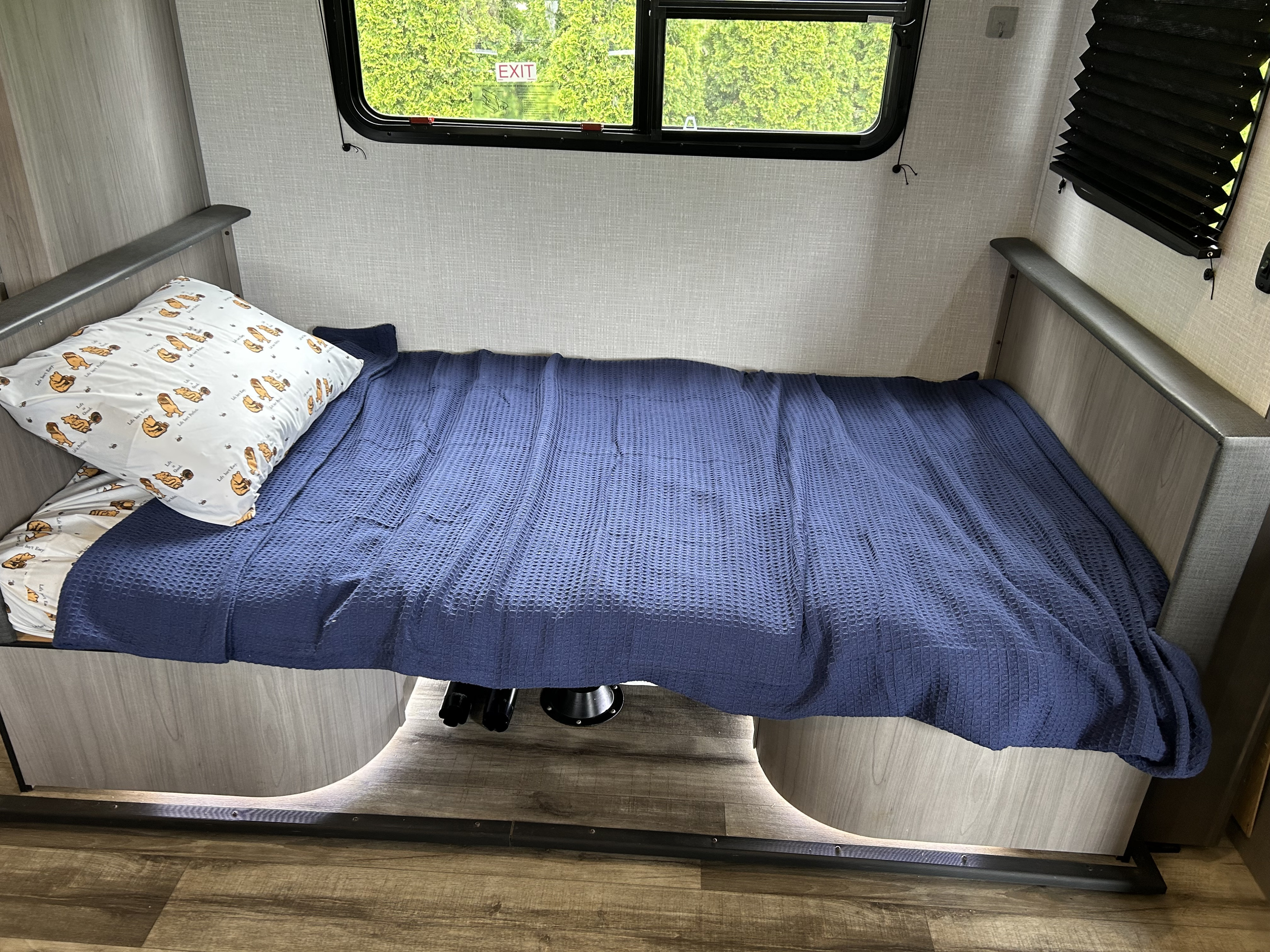 A comfortable sleeping area inside an RV rental, featuring a blue blanket and character pillow.. Dutchmen Coleman Light 2022