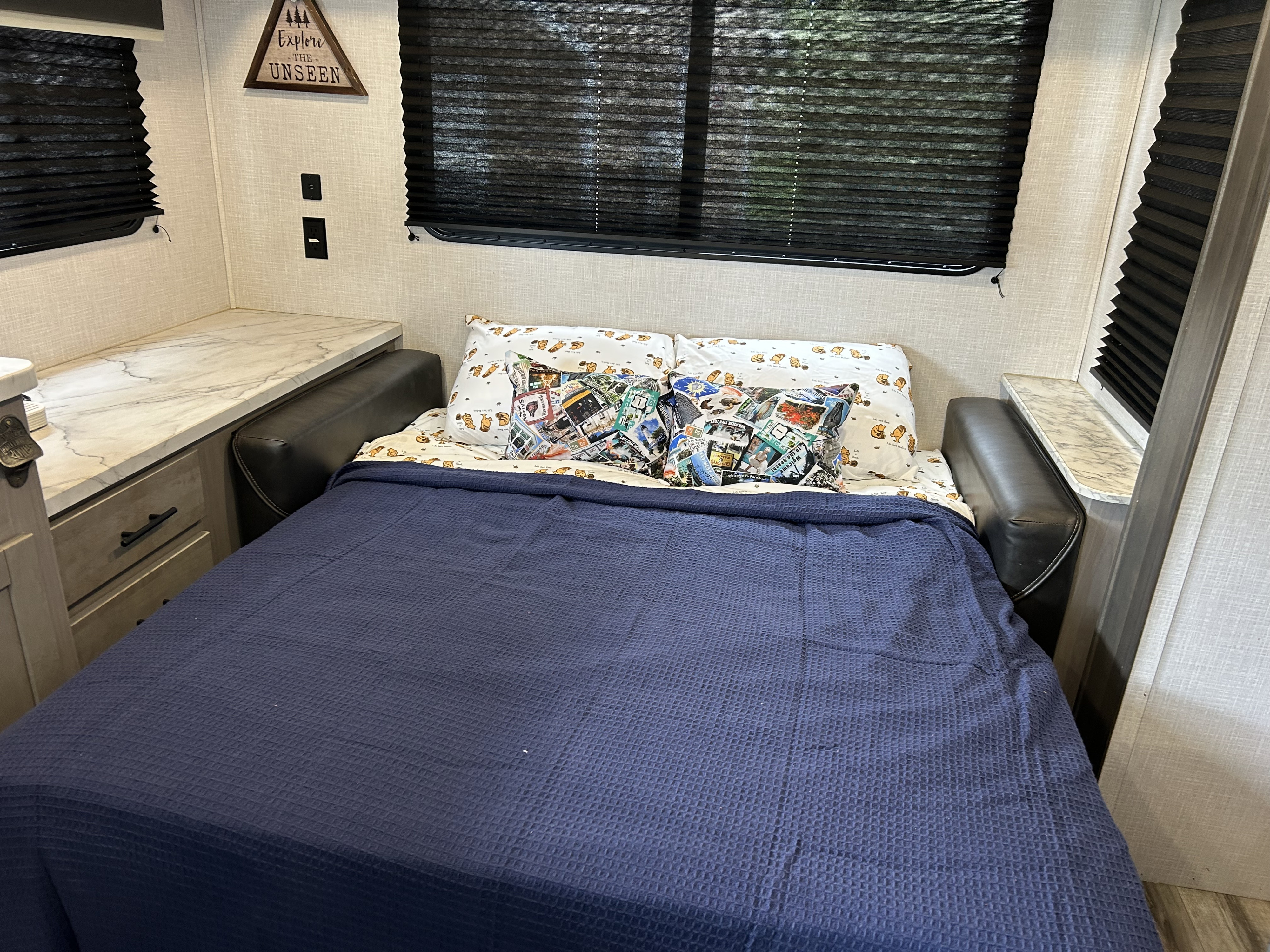 This RV rental's sleeping area is set up with a cozy bed, plush pillows, and built-in counter space with storage.. Dutchmen Coleman Light 2022