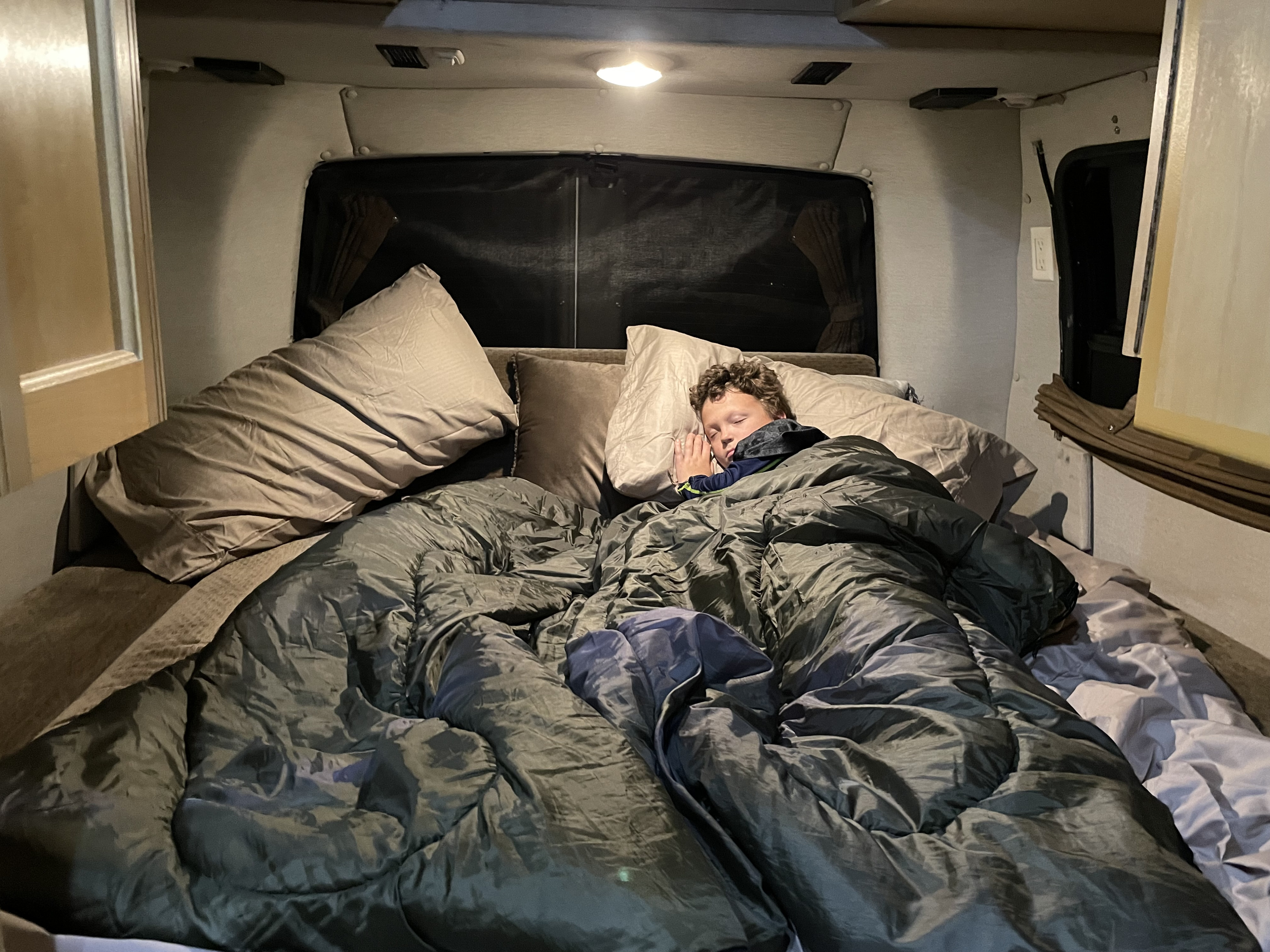 Boy peacefully sleeping in a cozy bed inside an RV rental. Ideal for family road trips & comfort.. Roadtrek 210 - Popular 2005