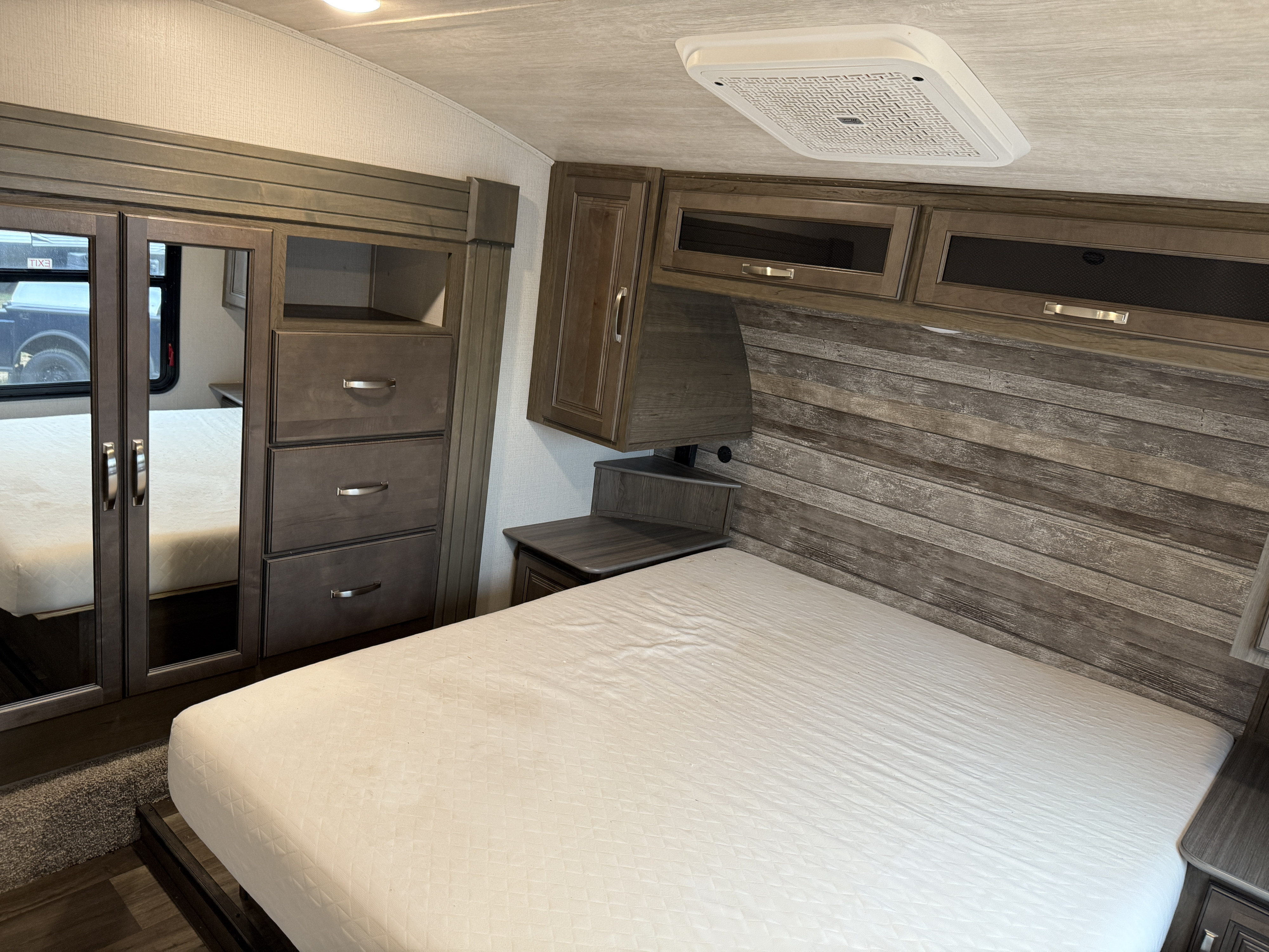 An inviting RV rental bedroom with a large bed, built-in wardrobe, drawers, and overhead cabinets, ideal for travelers.. Keystone Cougar 2023