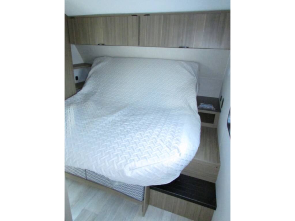 This RV rental bedroom offers a comfortable bed, overhead cabinets, and bedside storage for your journey.. Forest river Salem Cruise lite 2025