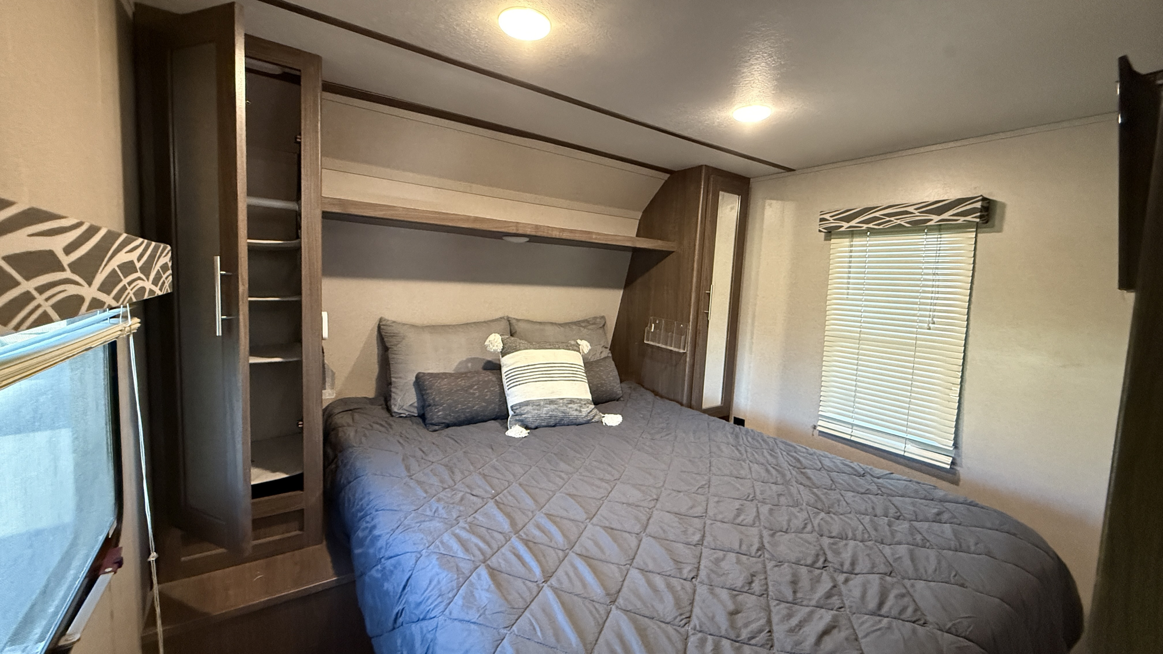 Cozy RV rental bedroom with queen bed, ample storage, and window blinds. A comfortable sleeping area for travel.. Keystone RV Hideout 2019