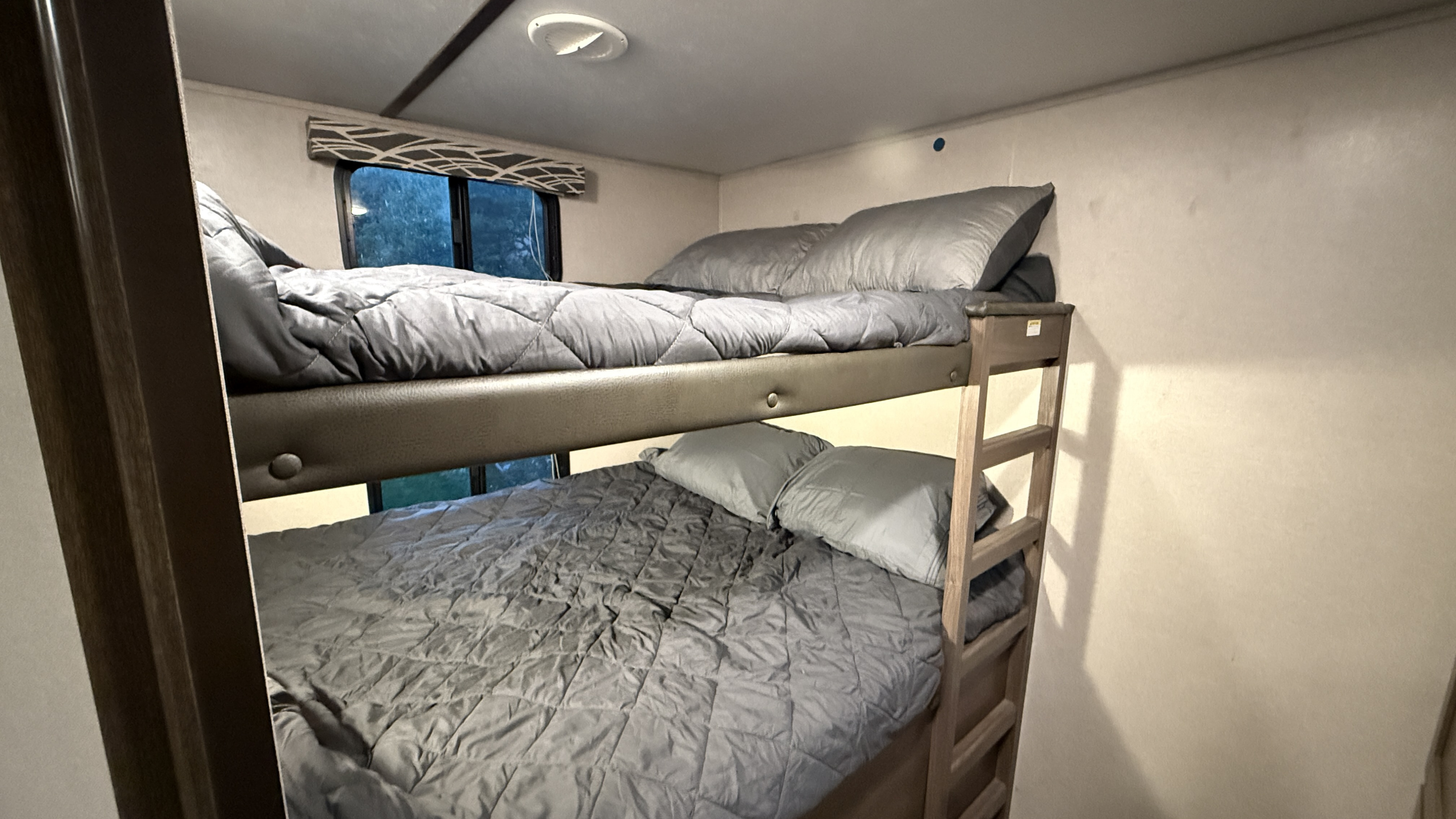 RV rental: Two comfortable bunk beds with grey bedding and a window. Perfect compact sleeping area for family trips.. Keystone RV Hideout 2019